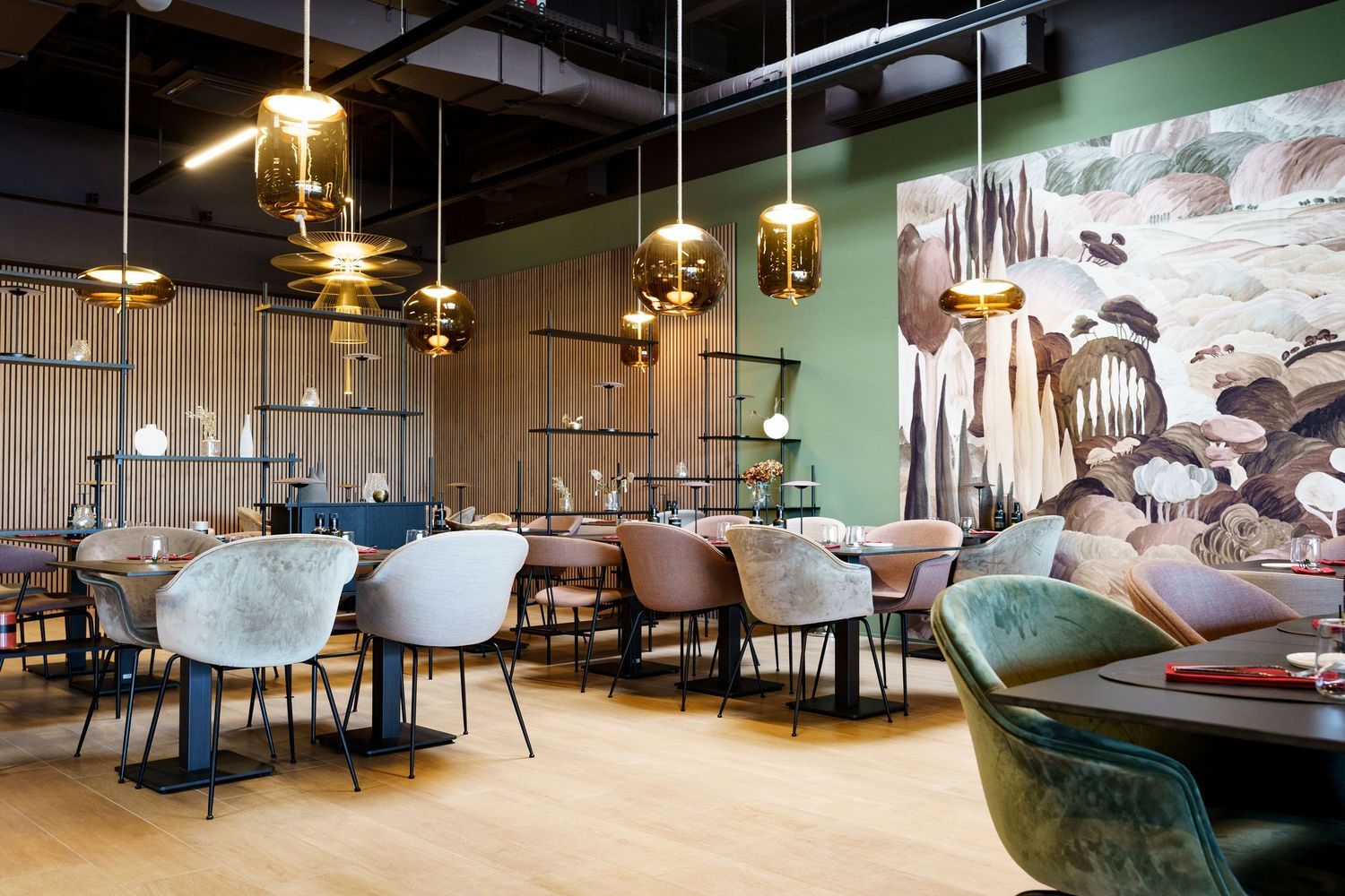 Modern restaurant interior with gold pendant lights, mixed seating, and a large nature-inspired wall mural.
