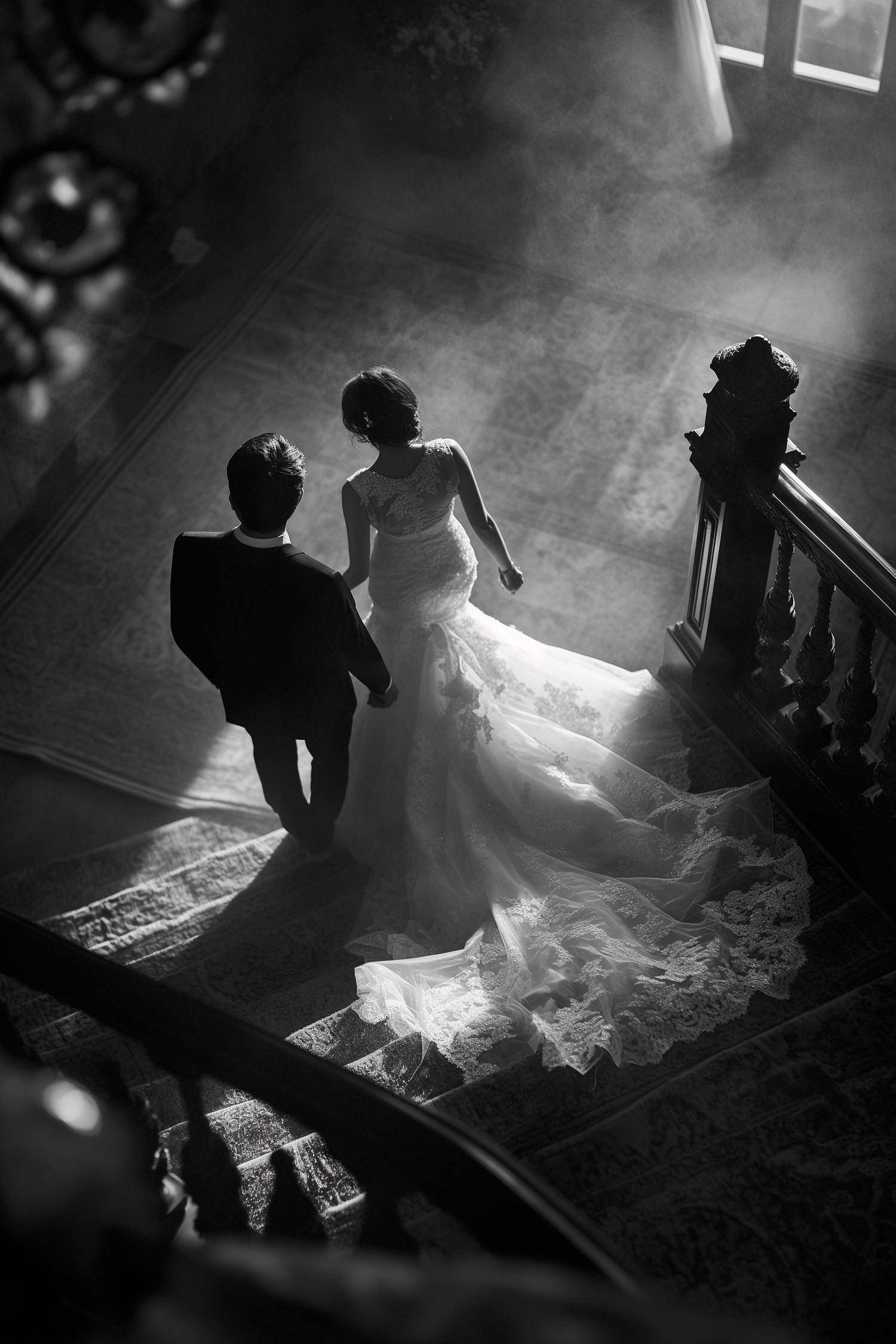 Black and white aerial view of bride and groom ascending a grand staircase.