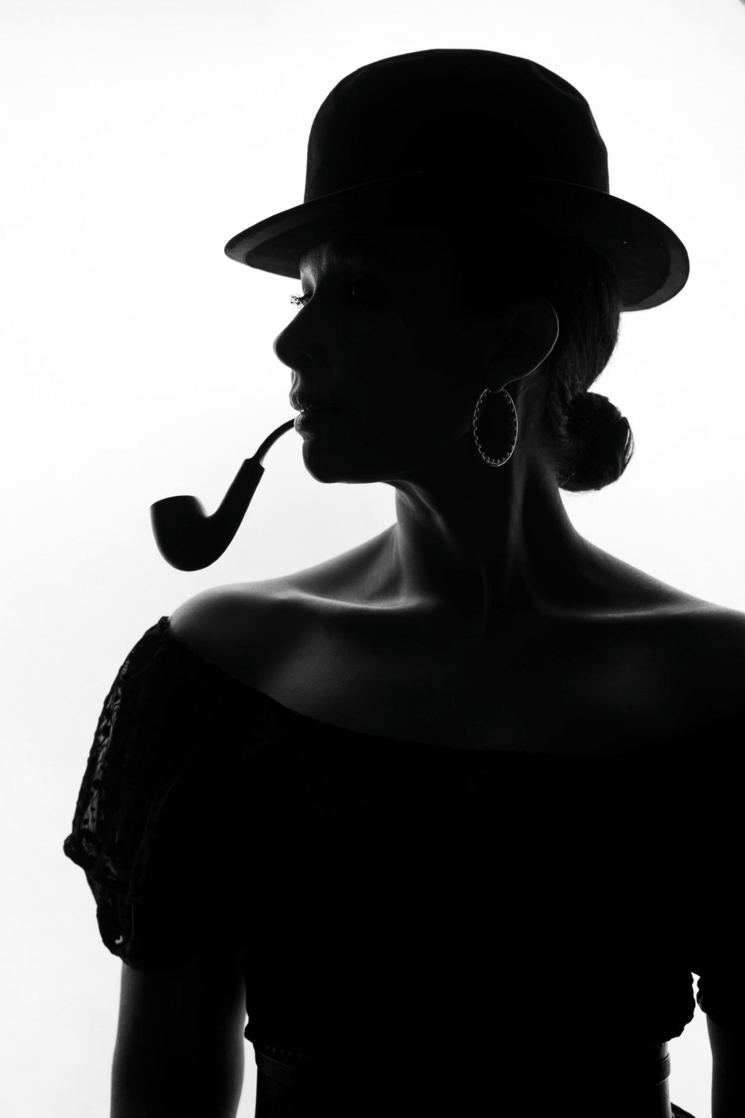 Black and white silhouette of a woman wearing a bowler hat and smoking a pipe.