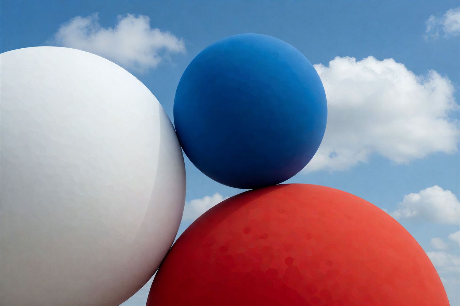 Three large white, blue, and red spheres against a cloudy blue sky.