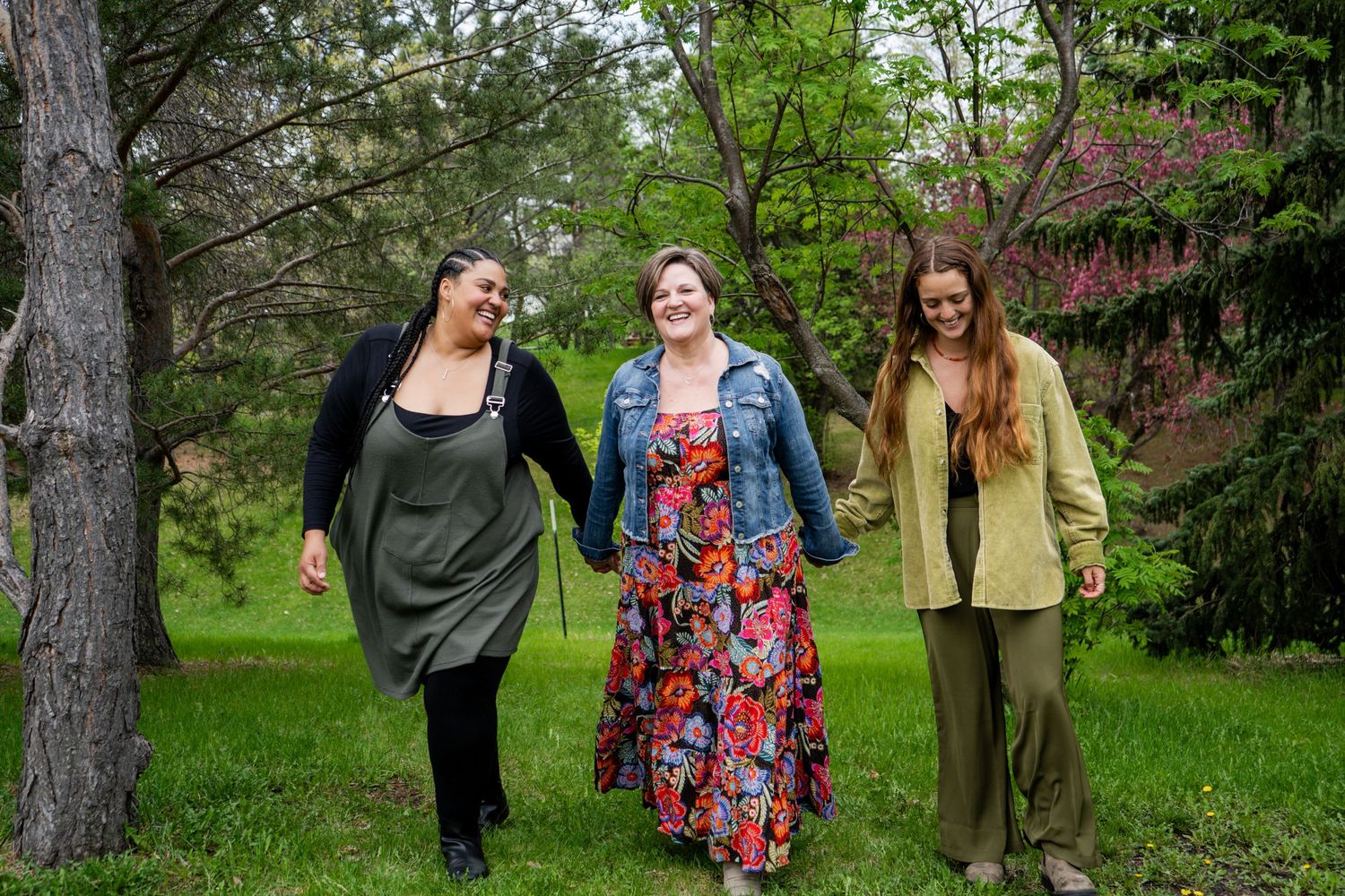 Three friends walking together through a lush spring garden.