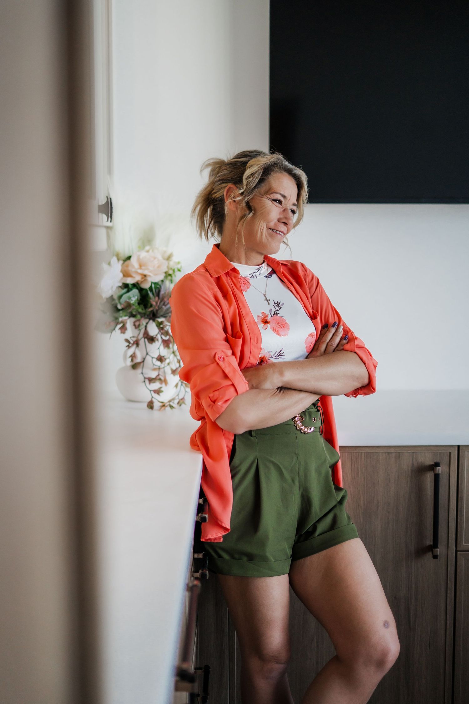 A series of dynamic poses in an orange shirt and green shorts against a white wall.