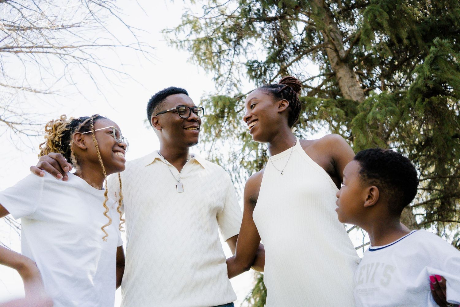 Candid outdoor family portraits showing natural interactions and joy under leafy trees.