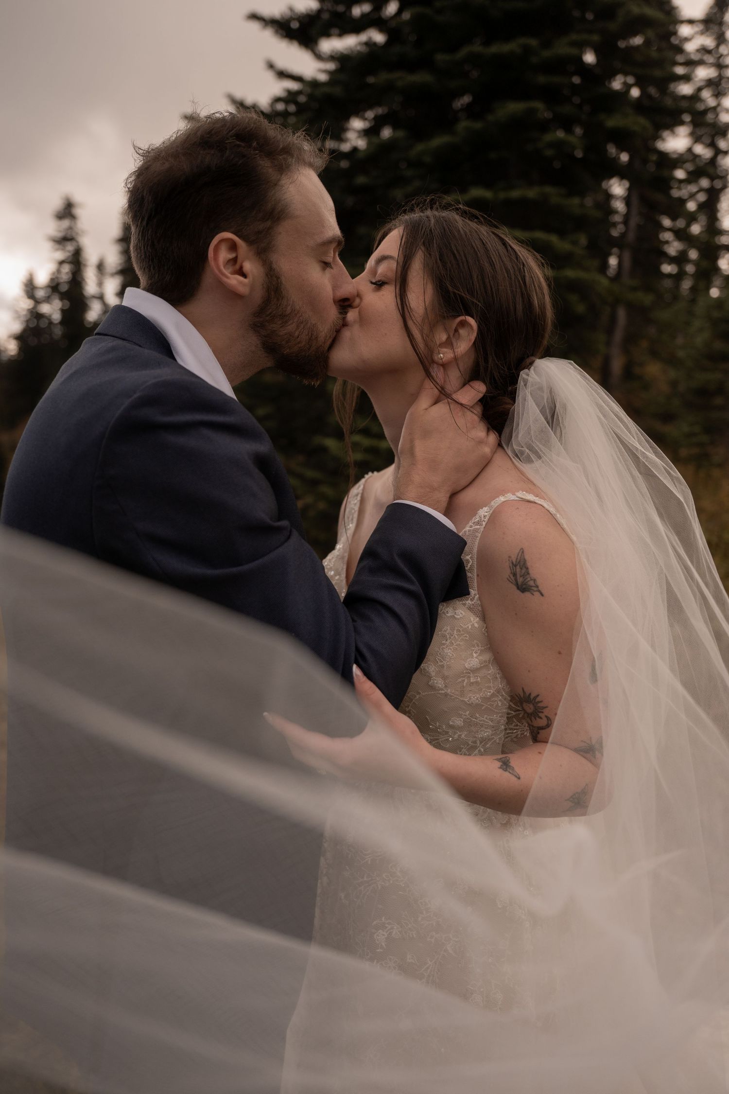 Newlyweds kiss during their elopement on a mountain.