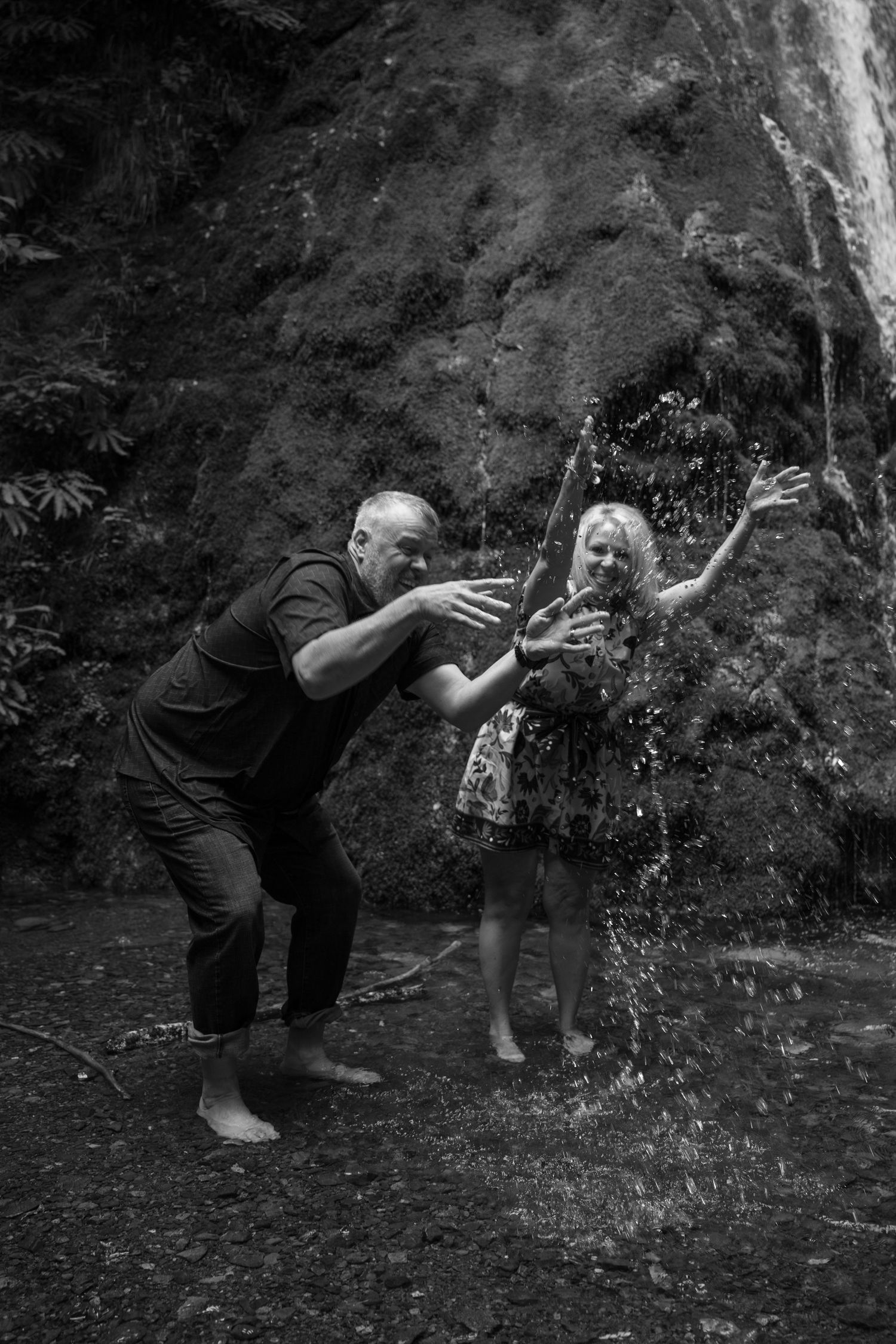A couple in their 50's splashes water from Madison falls in Olympic National Park while celebrating their 20th wedding anniversary.