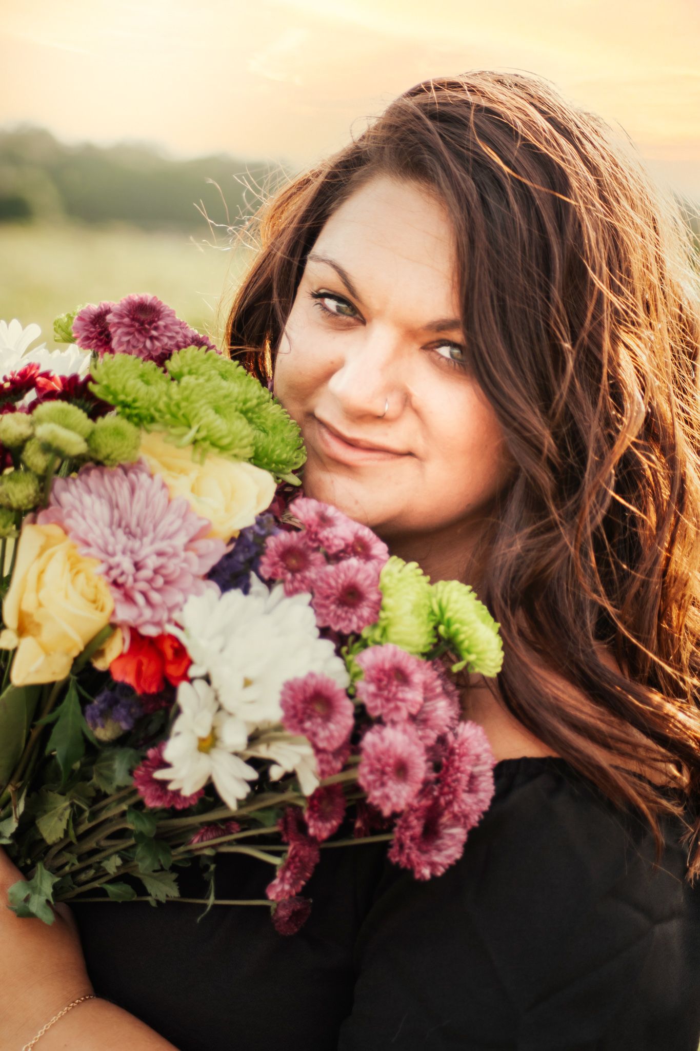 A woman looking over her shoulder while holding flowers.