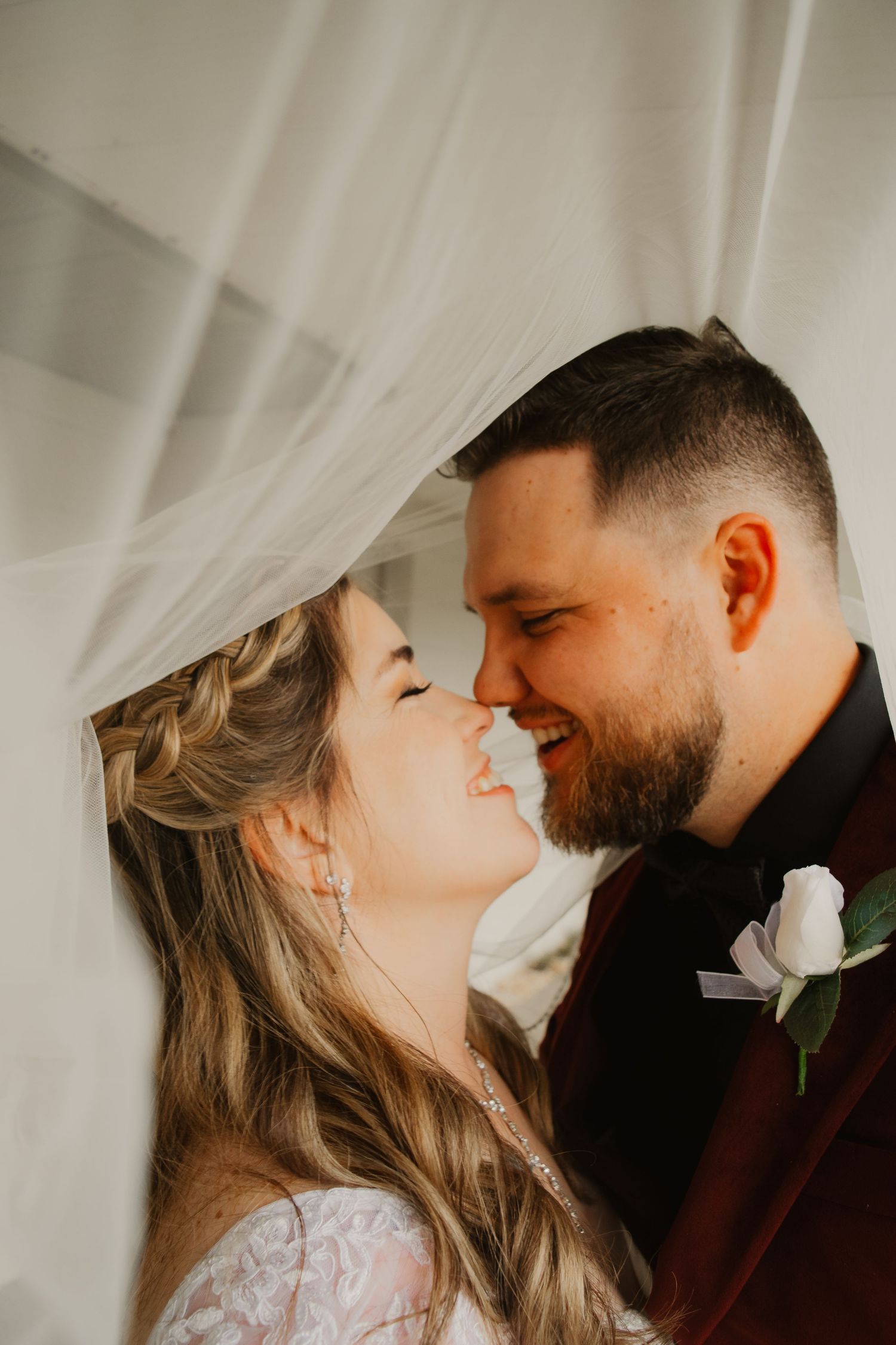 A romantic wedding photo series showing intimate moments between a couple through a flowing veil.