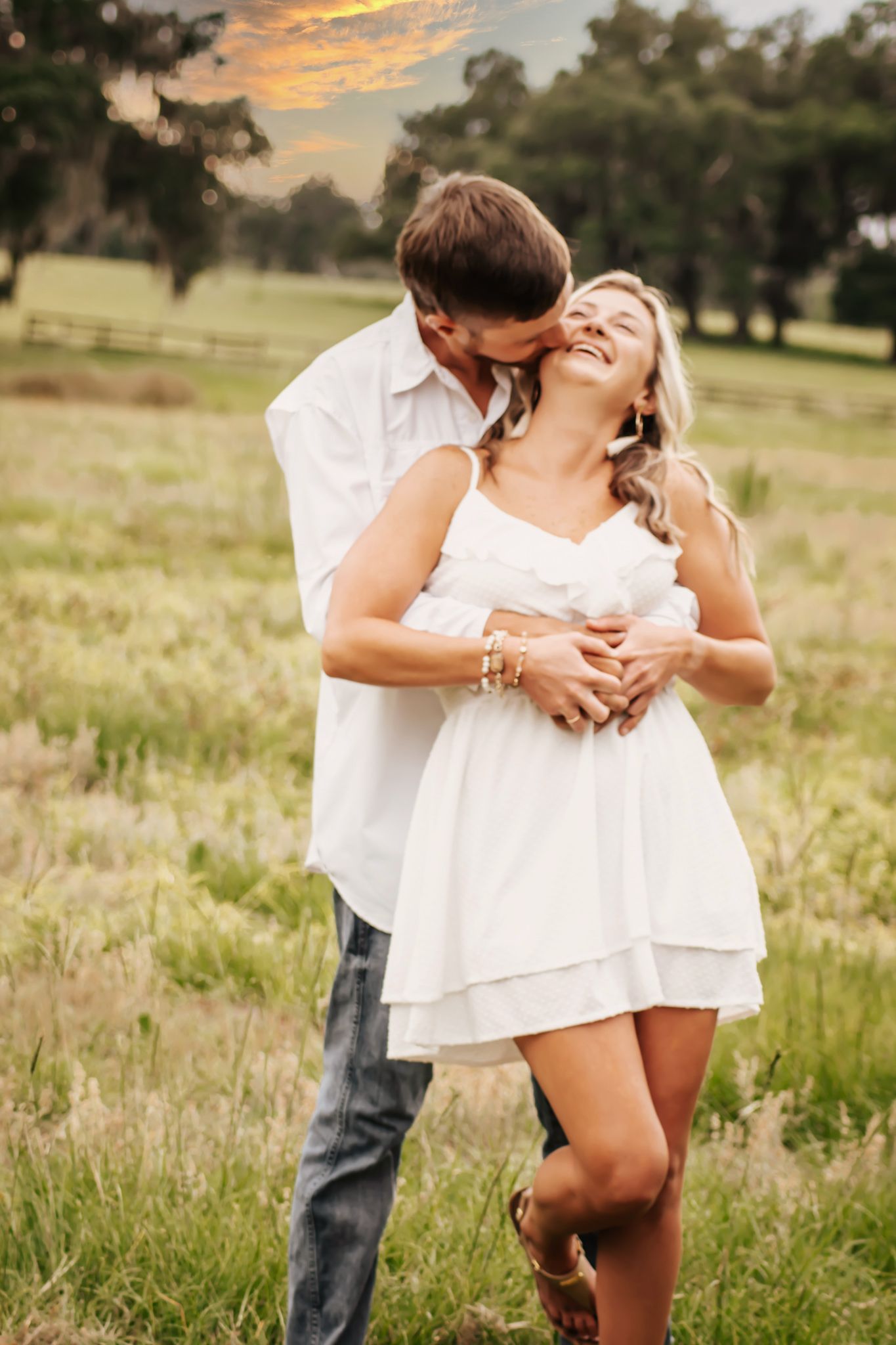 A romantic couple embraces in a sunlit field during golden hour, creating an intimate moment in nature.