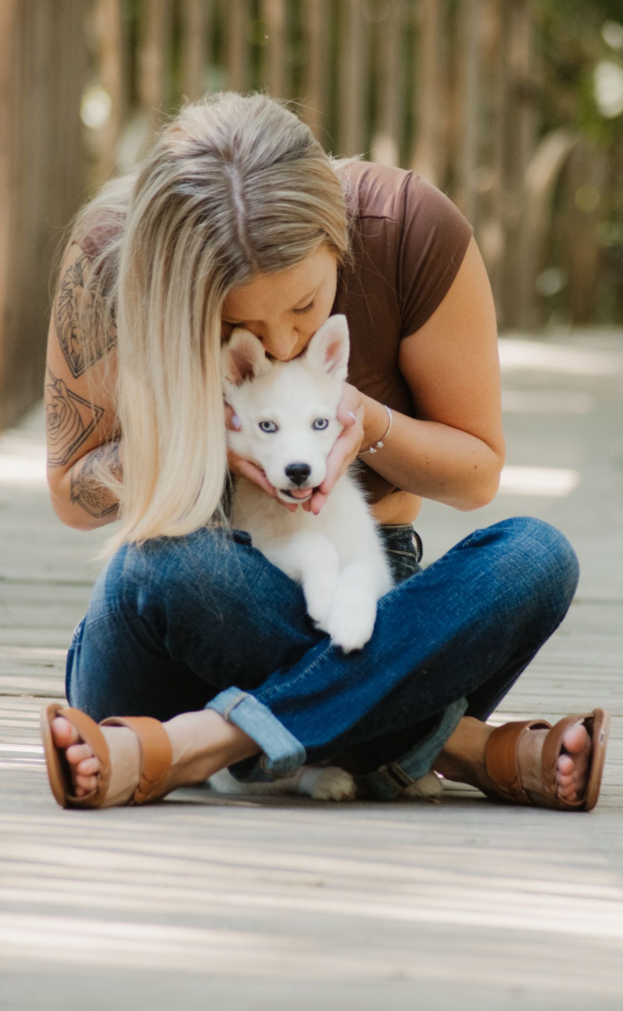 A woman in a brown top holds and plays with a fluffy white dog in a series of outdoor portrait photos.