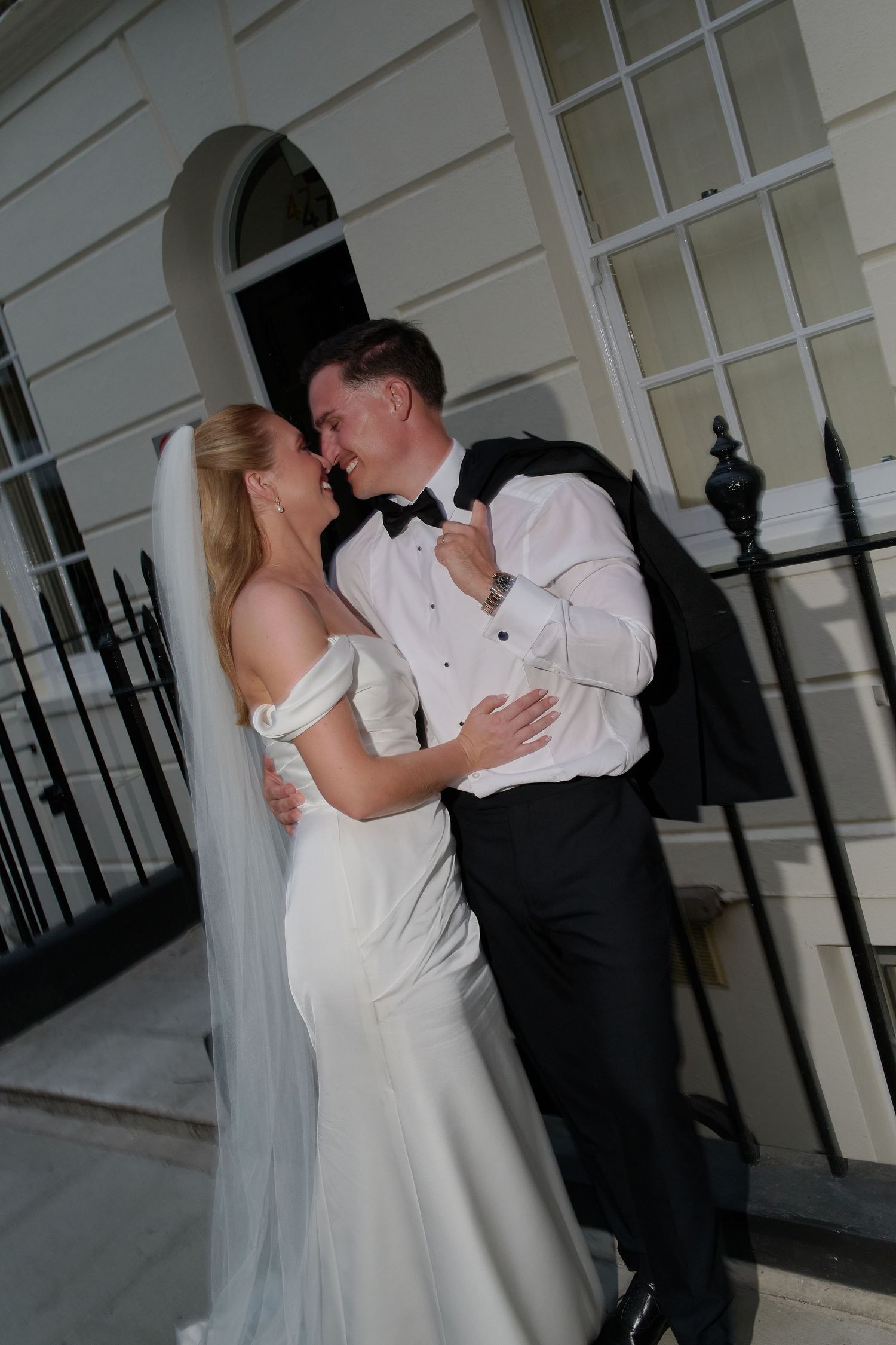 Bride and groom sharing a romantic moment outside a elegant white building, bride in white gown with veil.