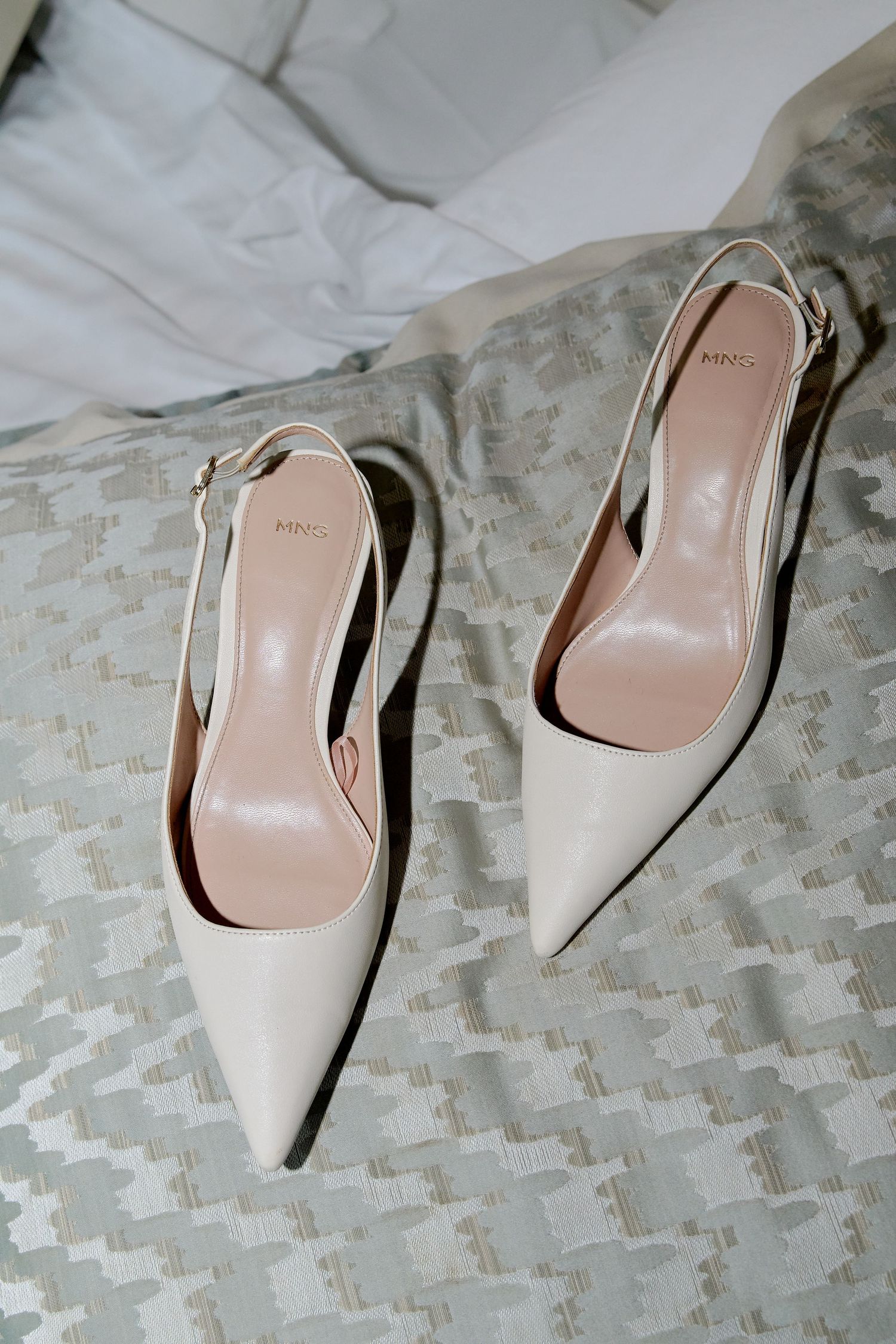 Elegant cream slingback pointed-toe heels by Mango displayed on a textured gray surface.
