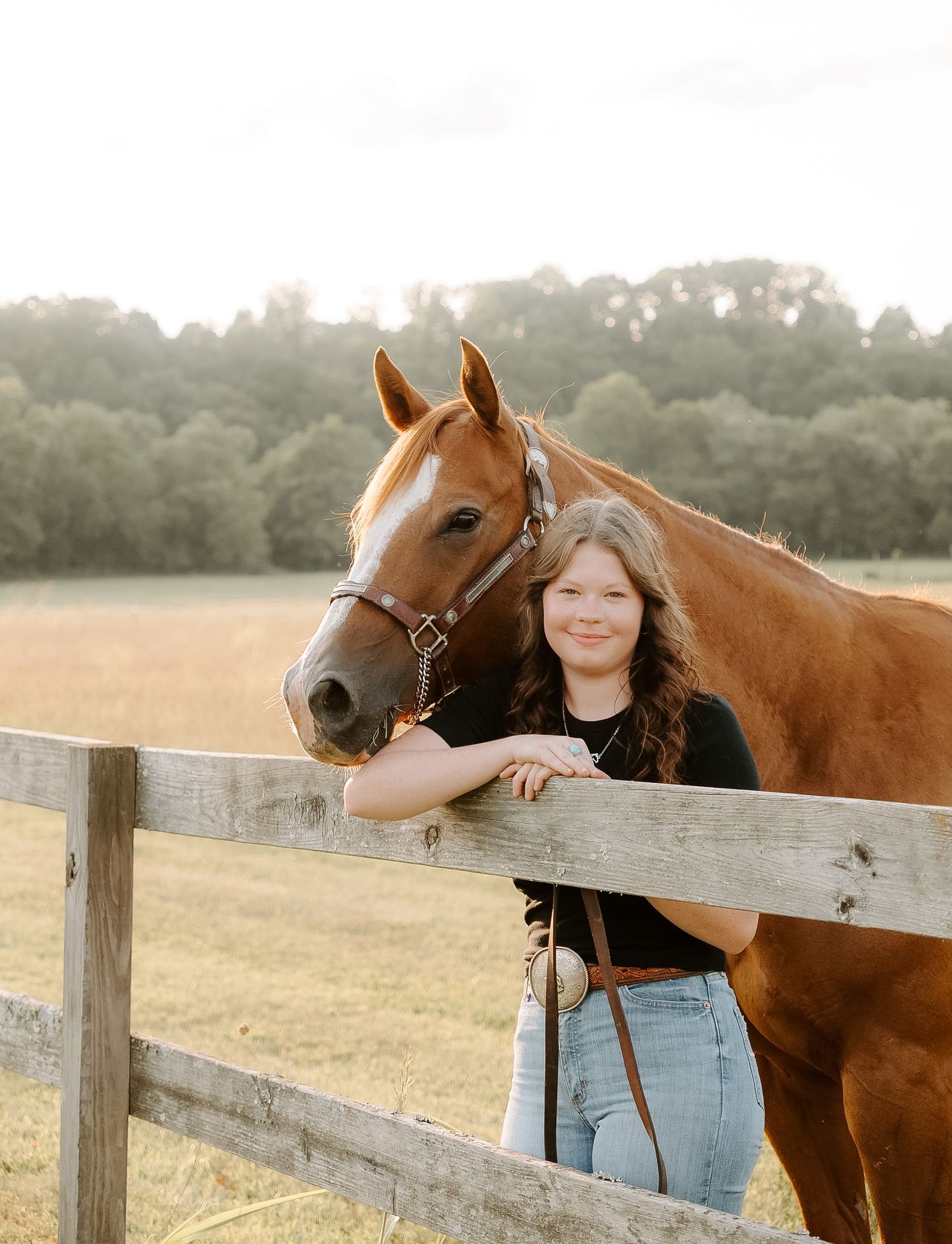 Girl leaned against a fence with her horse