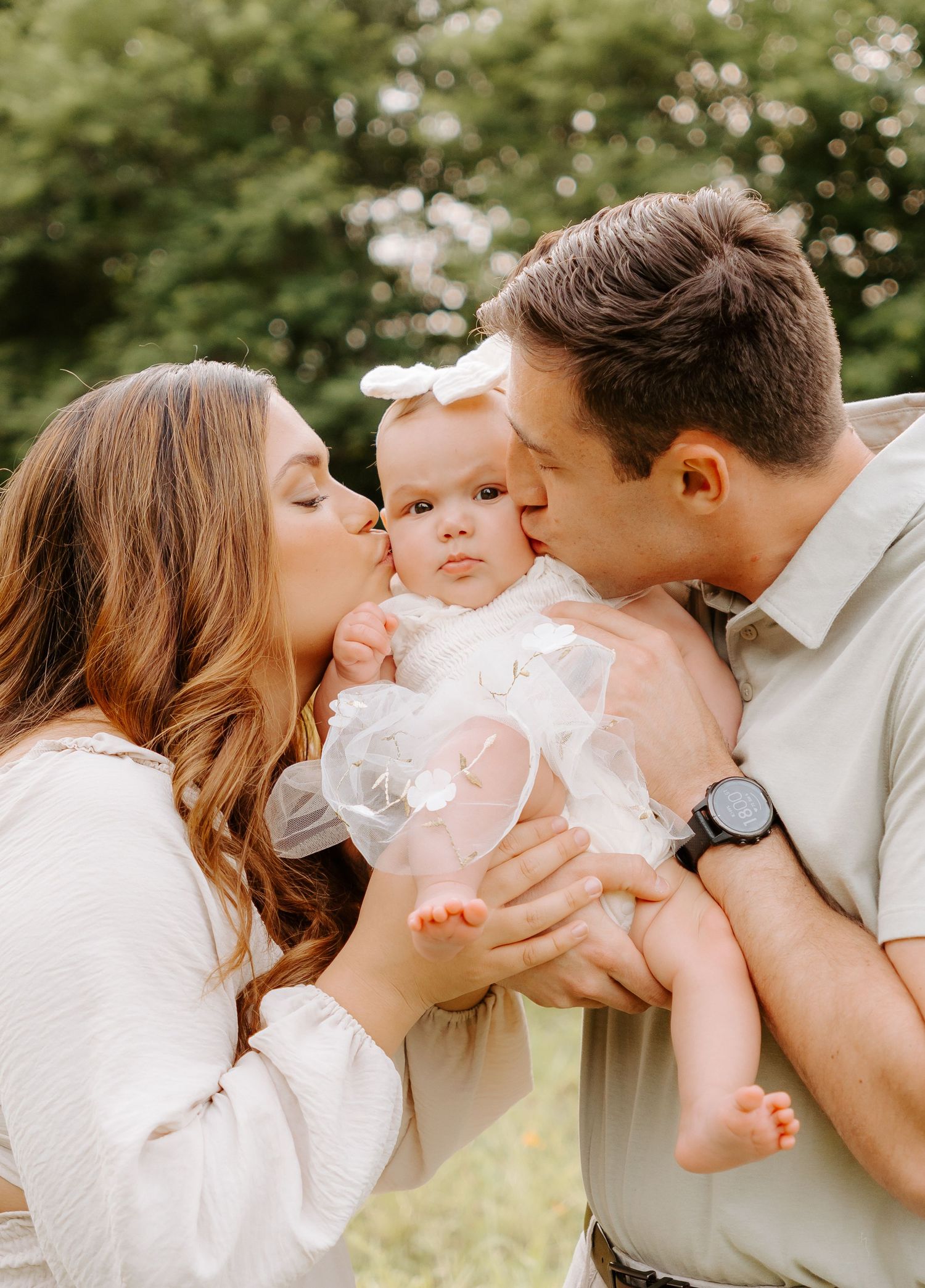 Dad and Mom kissing baby's cheeks