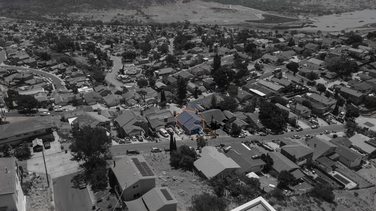 Aerial black and white drone view of a residential neighborhood with houses and tree-lined streets.