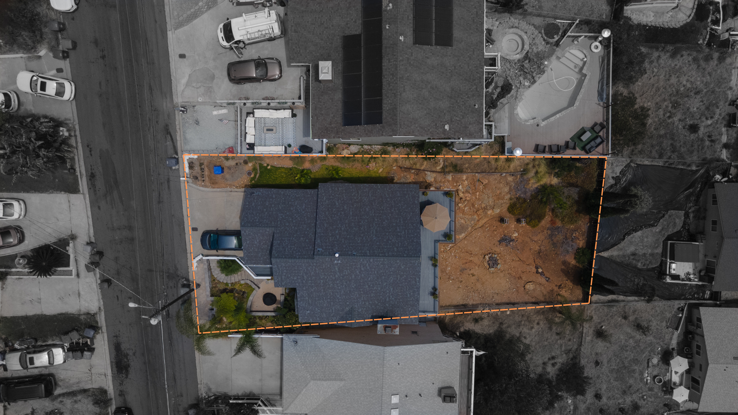 Aerial view of a residential property outlined in orange showing house, backyard, and surrounding neighborhood.