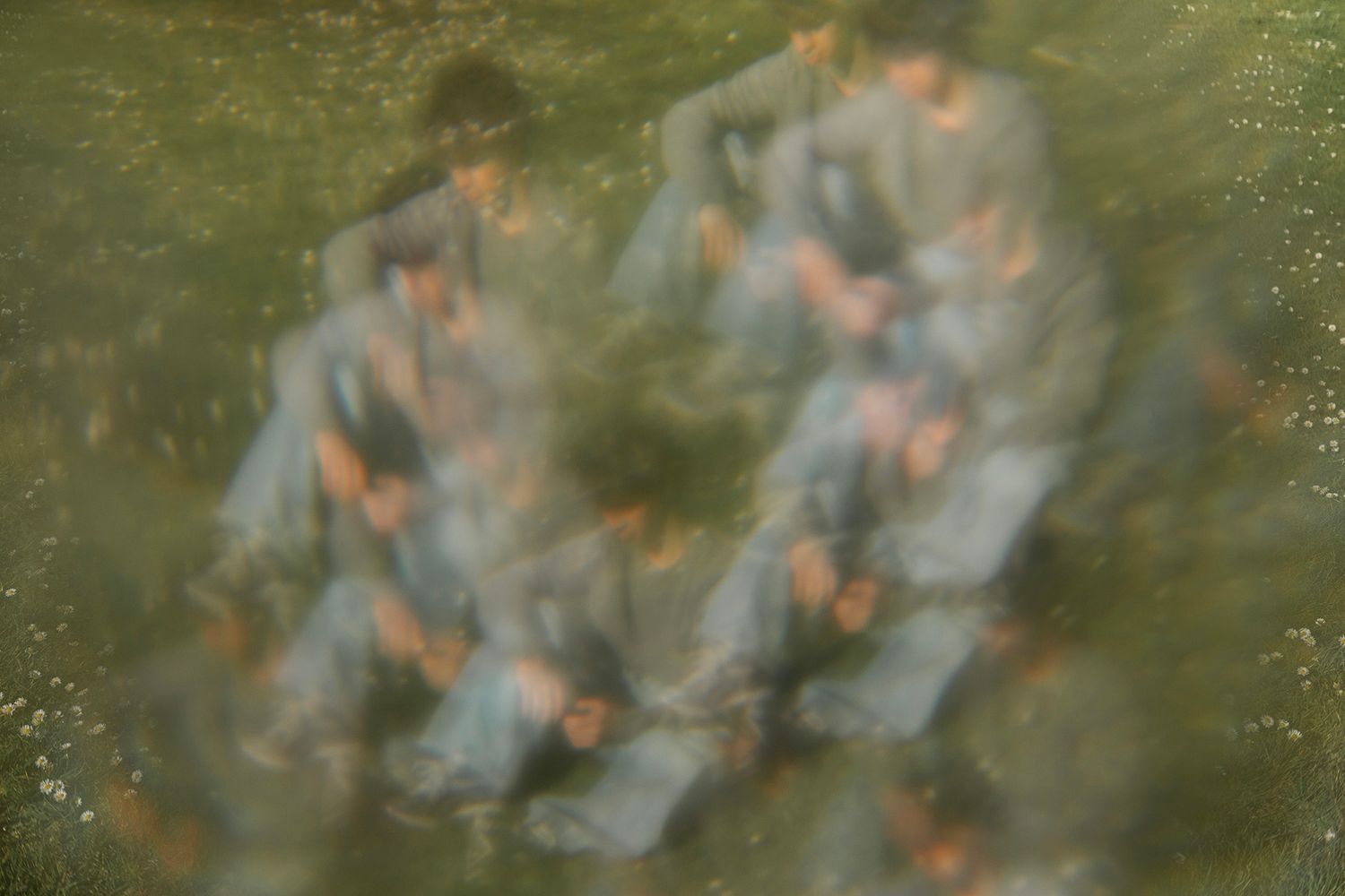 Blurred motion photo of people in blue clothing on green grass, creating an impressionistic, dreamy effect.