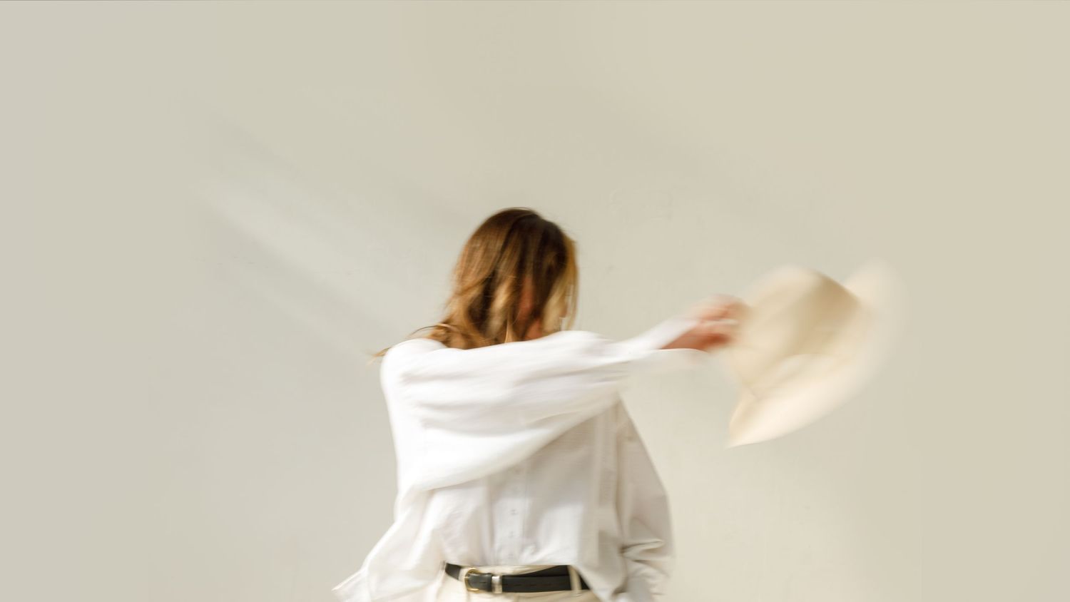 Woman in white button-down shirt spins dynamically against a clean white studio background.