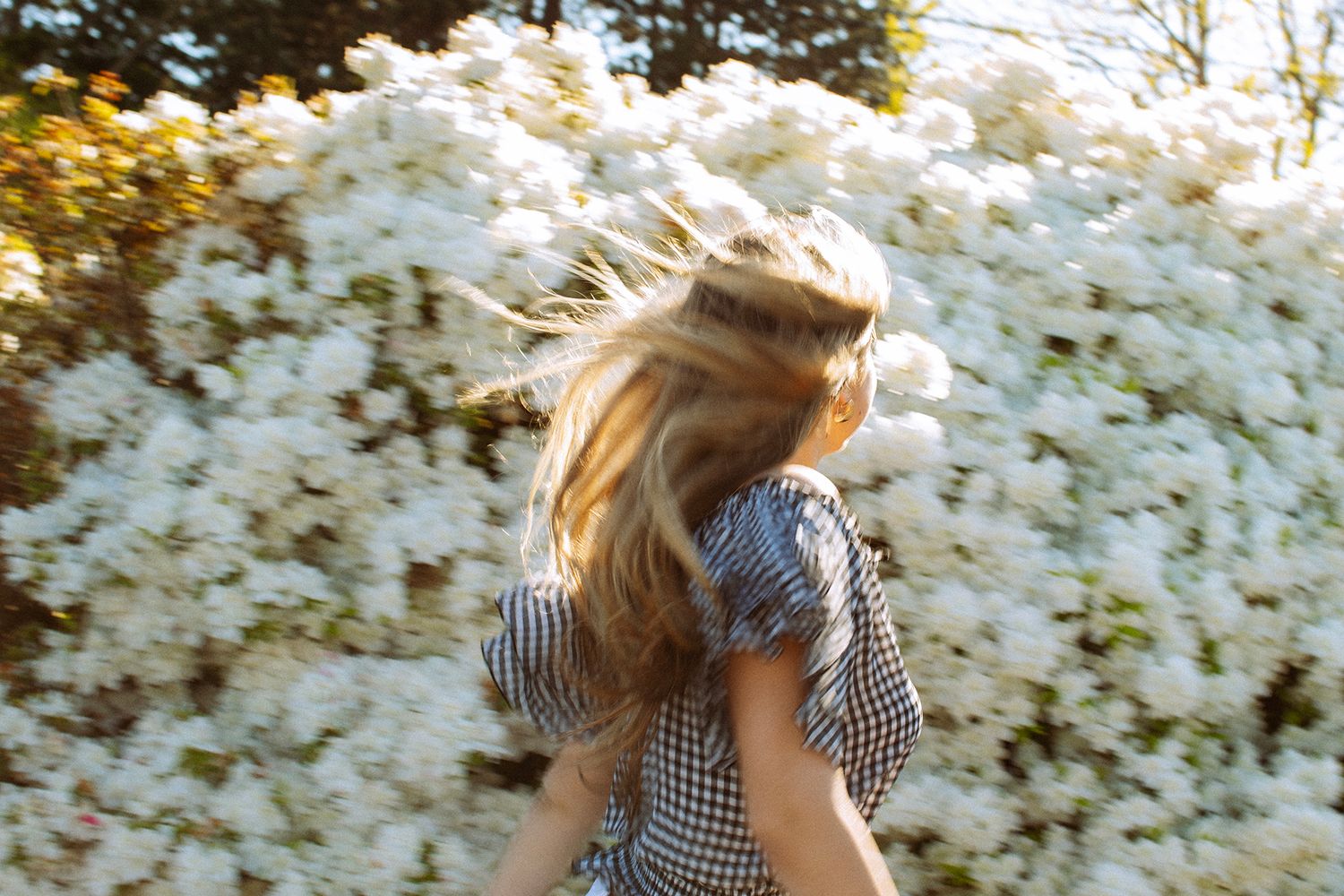 Blonde woman in white top and jeans standing in a mountain meadow with scenic valley views.