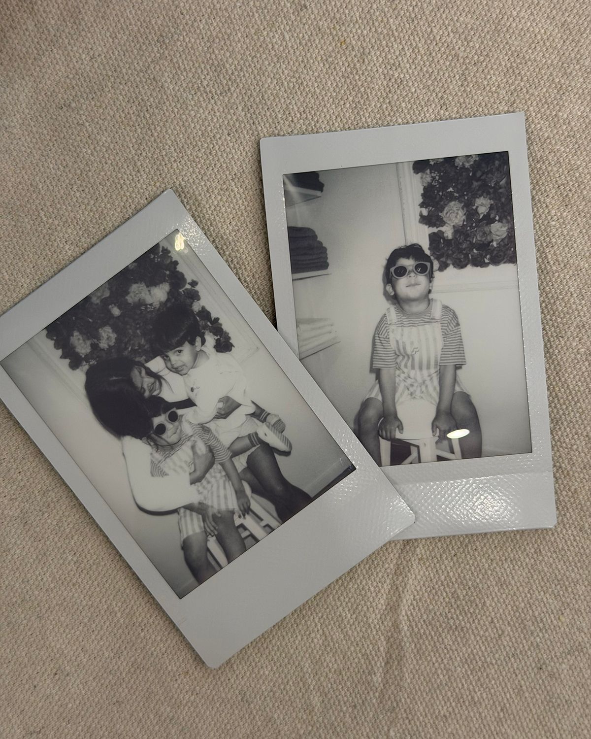 Two black and white Polaroid photos of a young child wearing oversized sunglasses, posing on a tricycle indoors.