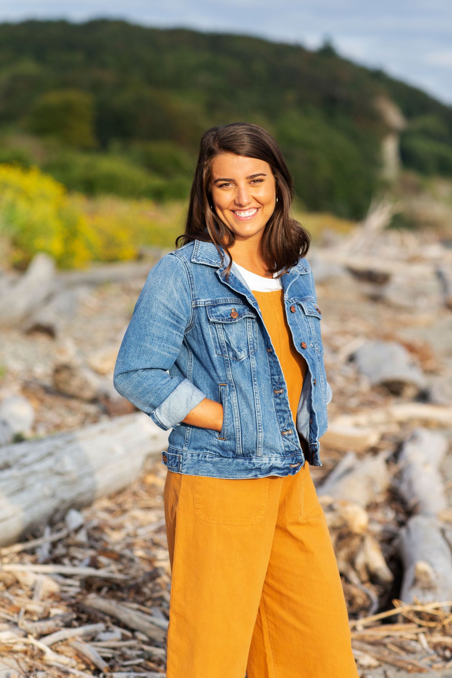 Senior Portrait girl wearing orange overalls and denim jacket with discovery park driftwood beach in background
