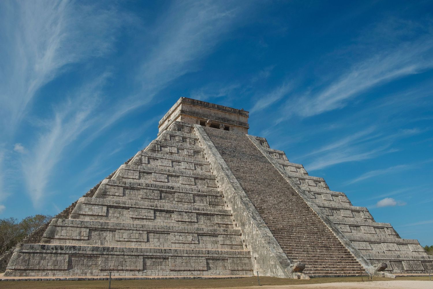 Ancient Mayan pyramid El Castillo at Chichen Itza under a bright blue sky with wispy clouds, Mexico.