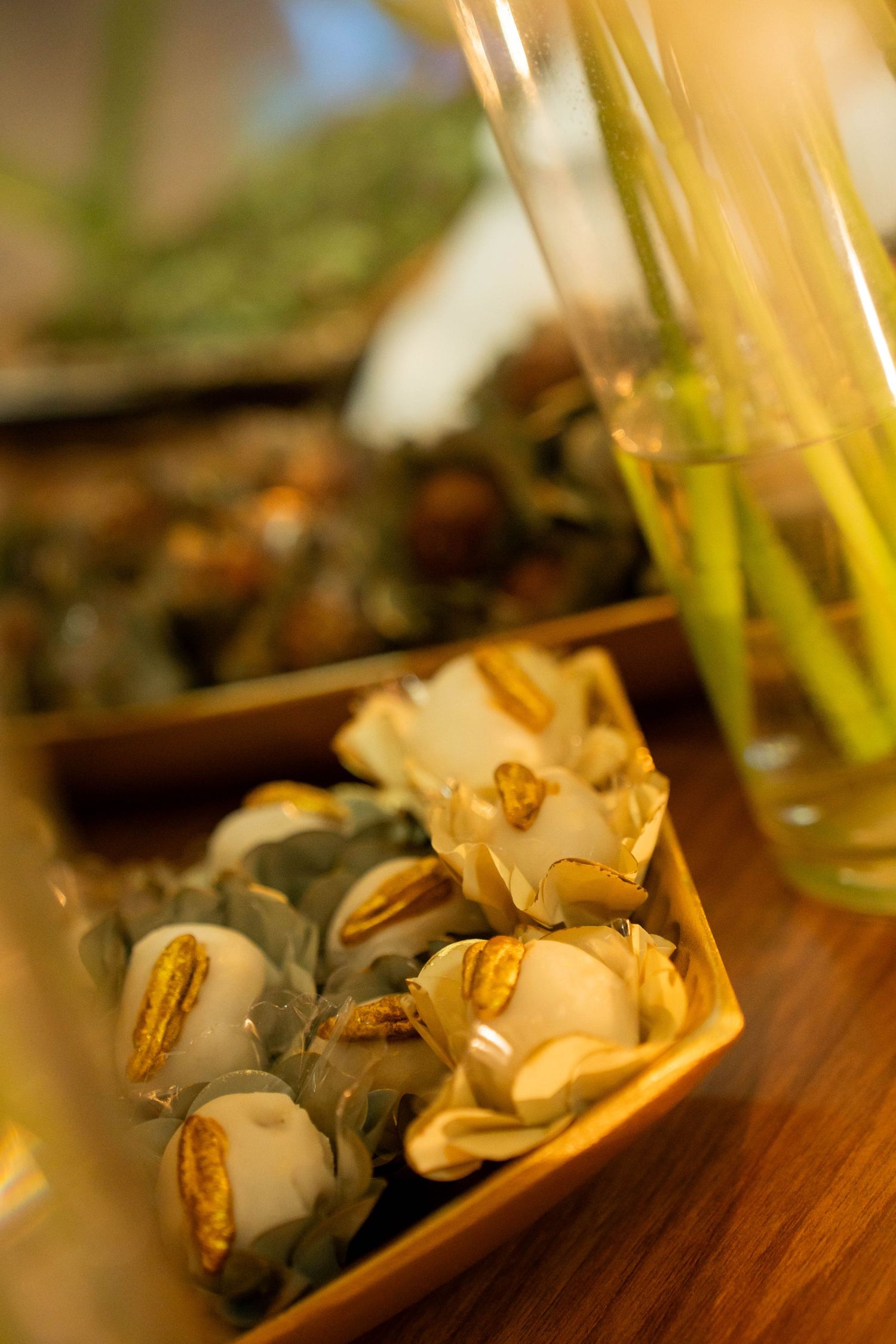 Close-up of elegant stuffed appetizers topped with seeds in a wooden serving dish on a warm-lit table.