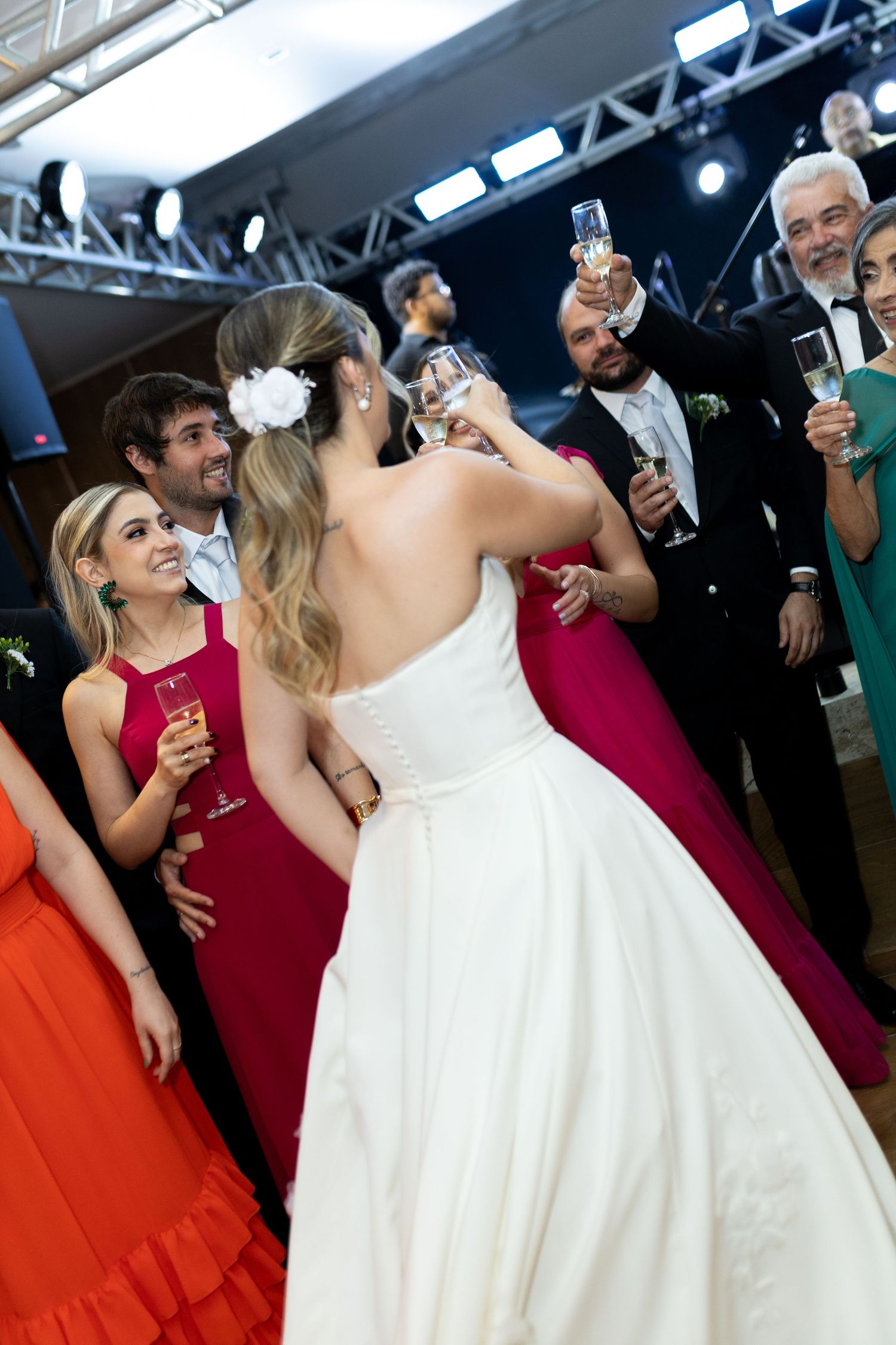 Bride in white gown toasting champagne with wedding guests in formal attire at a reception celebration.