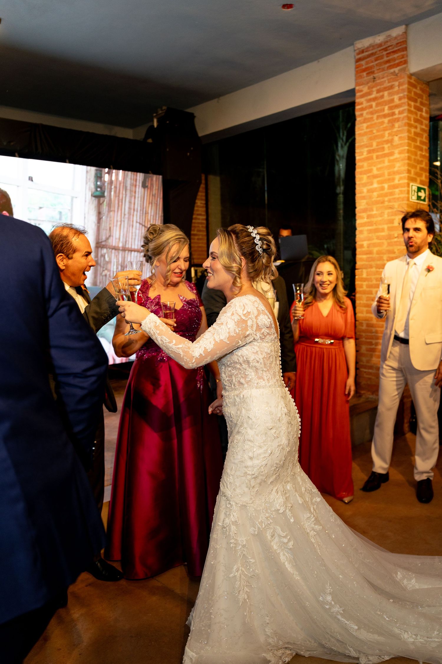 Bride in lace gown toasting with guests at elegant wedding reception venue.