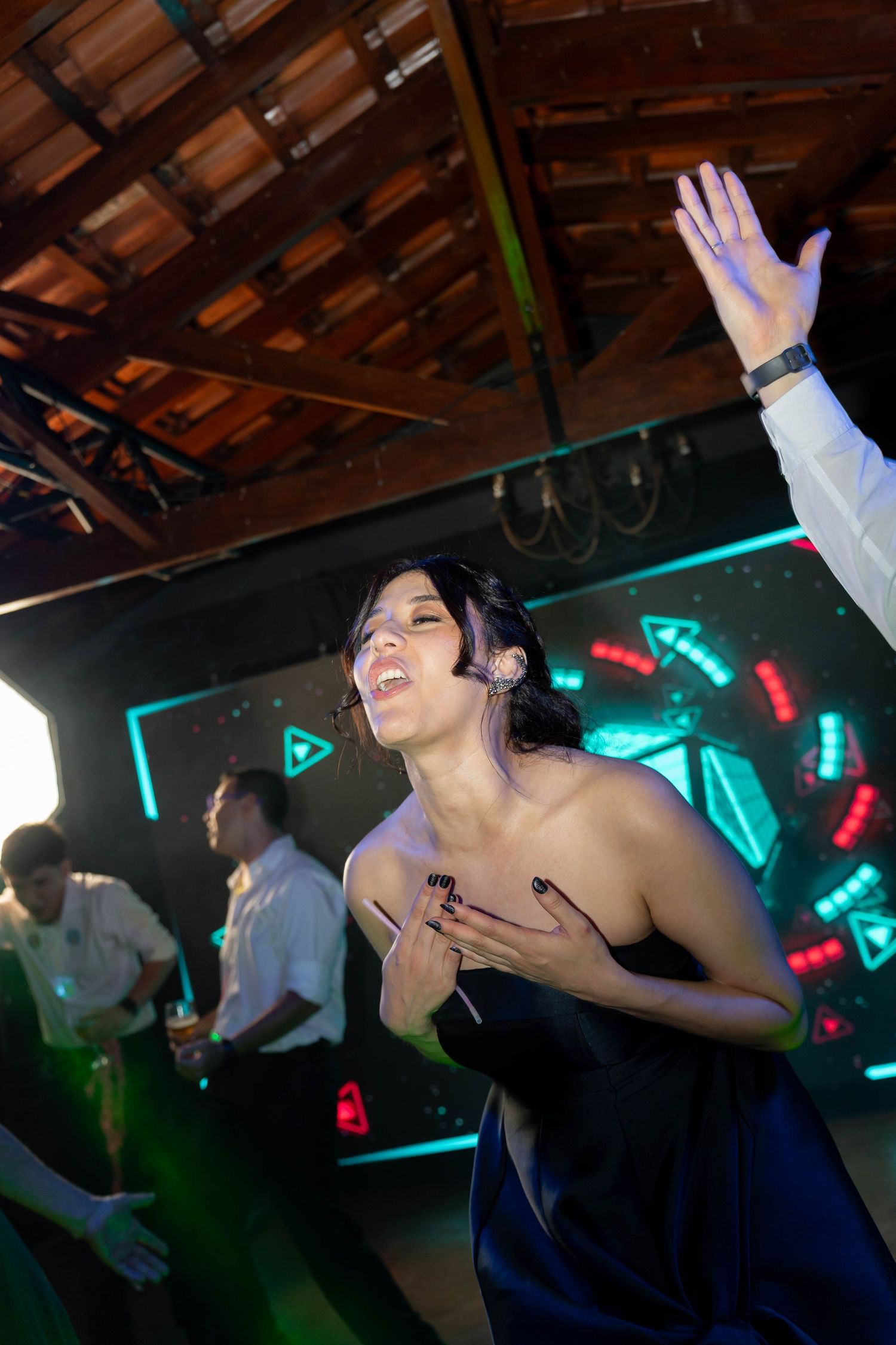Woman in blue dress dancing at a nightclub with neon lights and other guests in the background.