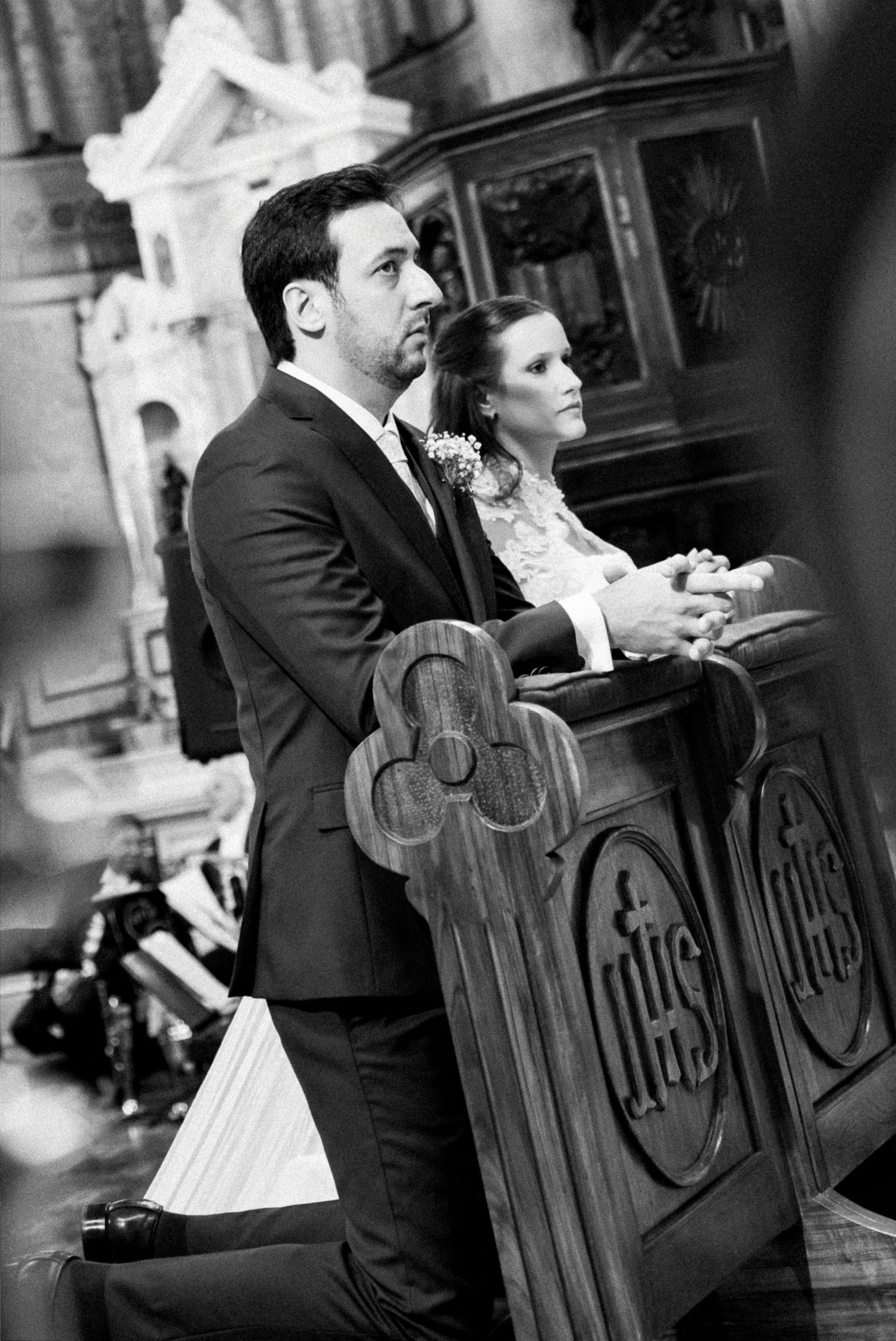 Black and white photo of a couple kneeling at a church altar during a wedding ceremony.