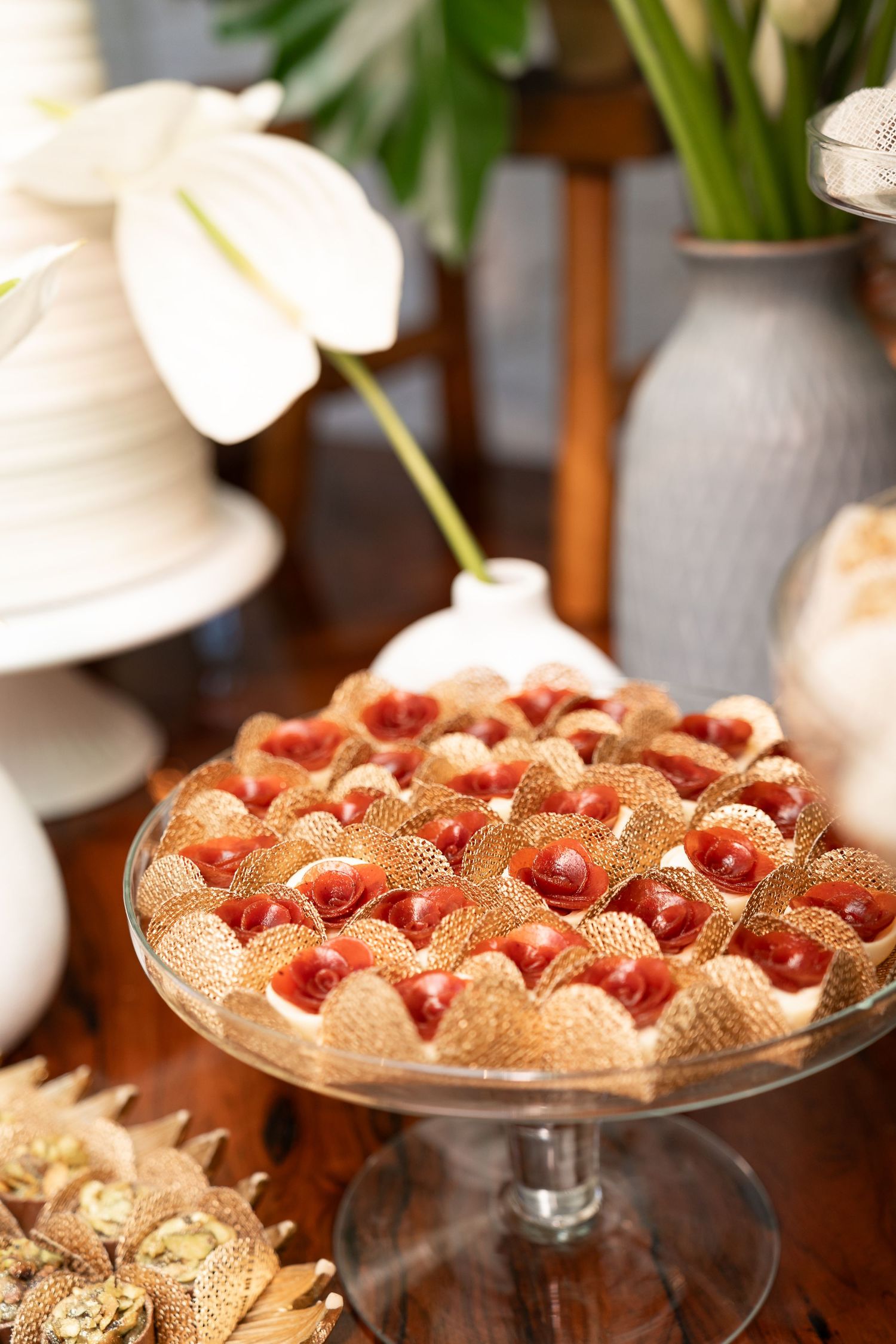 Elegant dessert display featuring strawberries in golden waffle cups on a glass pedestal stand at a wedding reception.