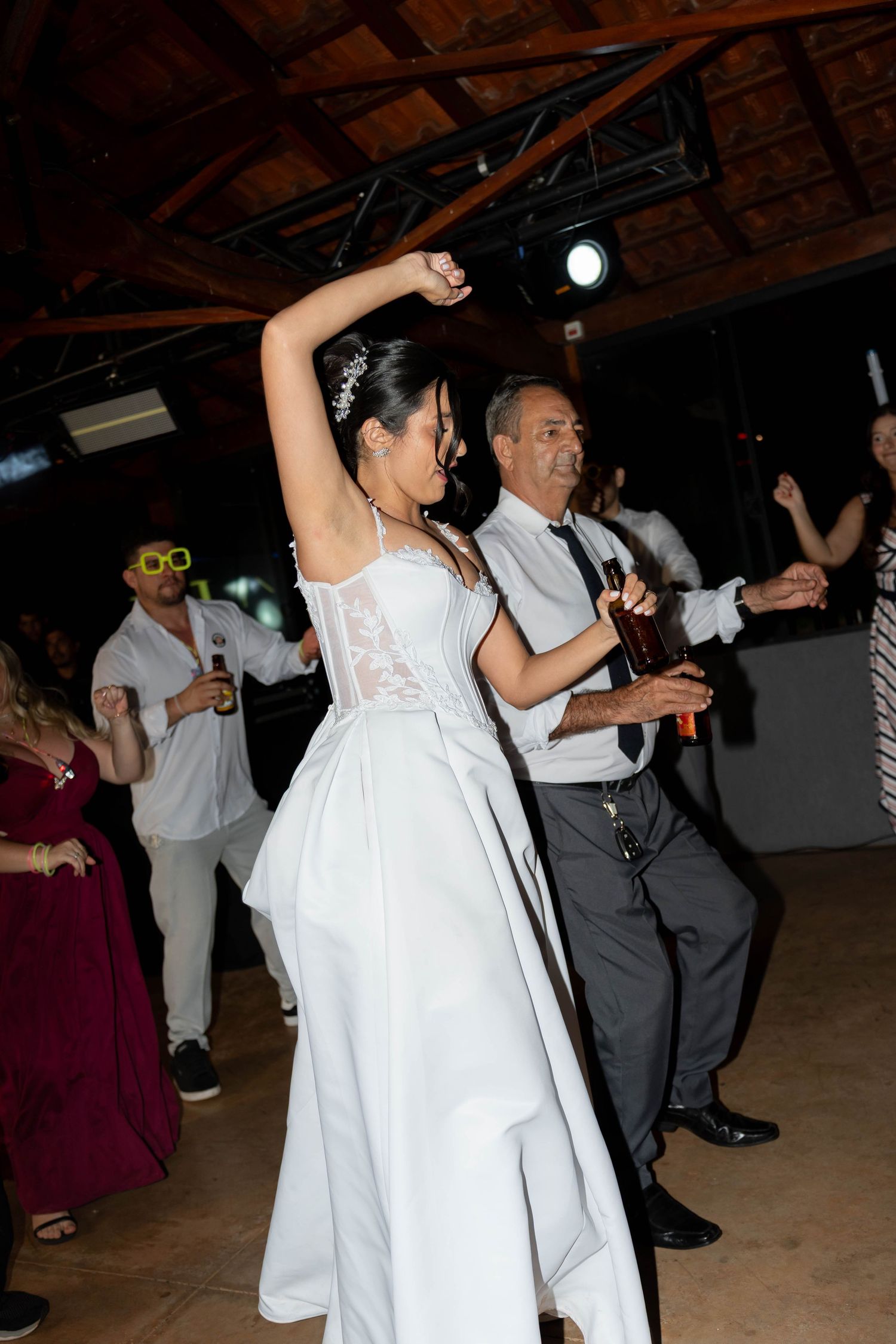 Bride in white gown dancing joyfully with guests at a wedding reception party.