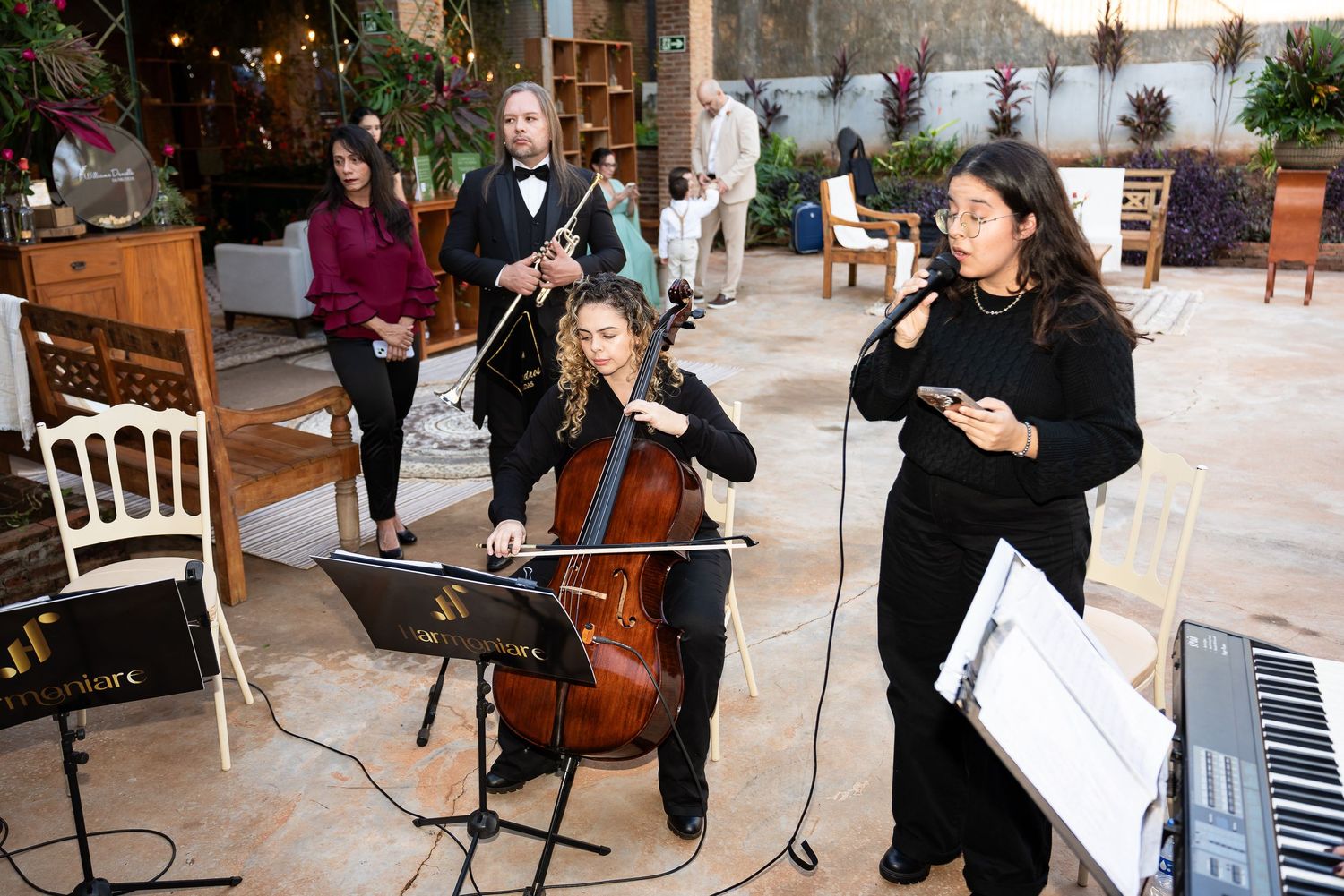 Live band performing at elegant event with cellist, flutist, and vocalist in decorated indoor venue.