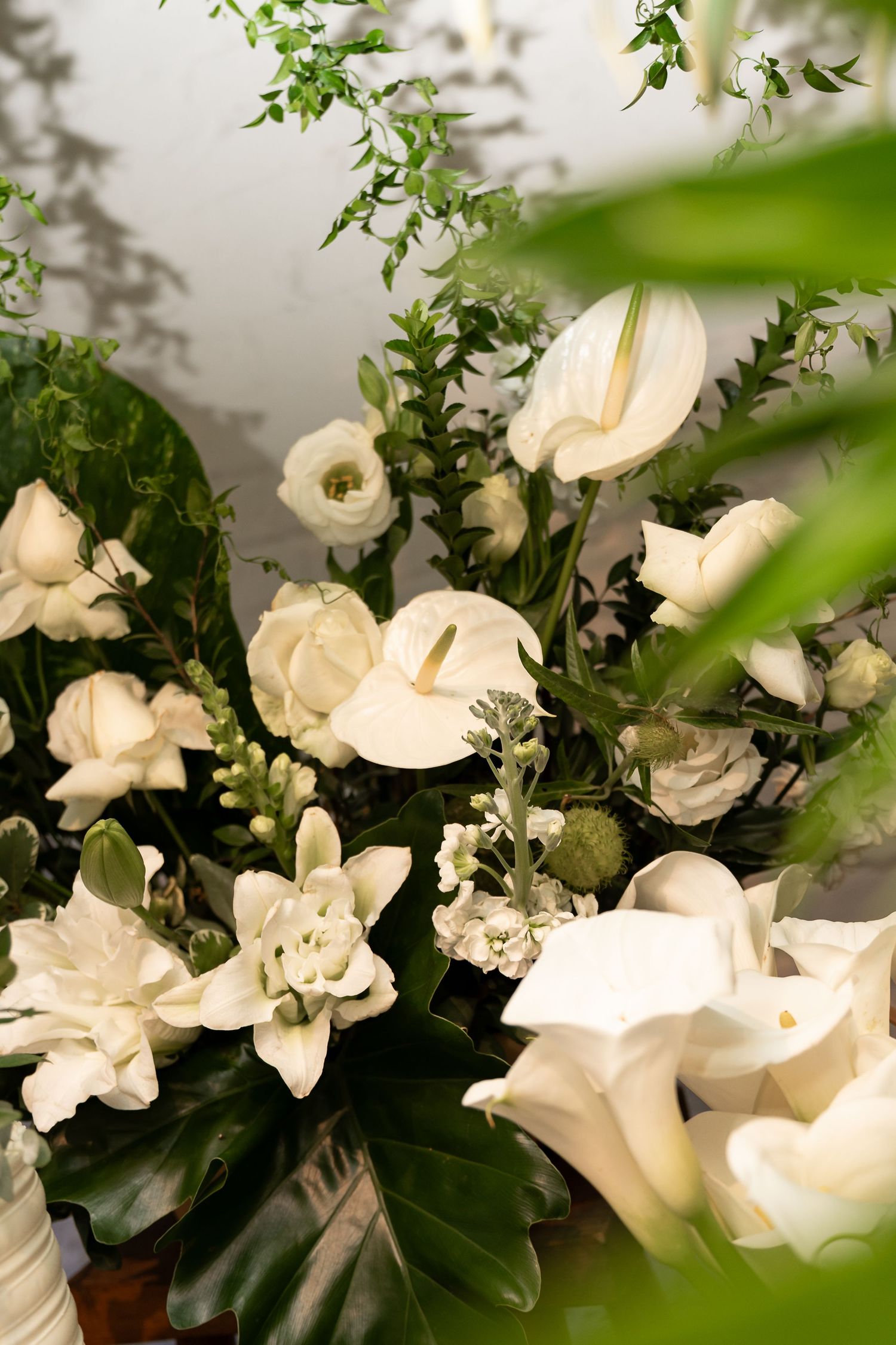 Elegant white floral arrangement featuring calla lilies, roses, and greenery for a wedding or special event.