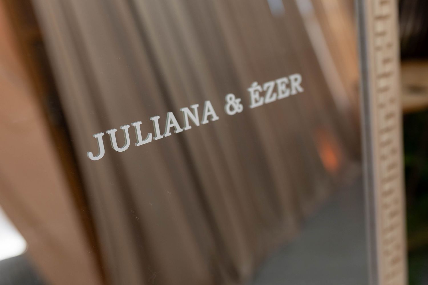 Close-up of a wedding album cover engraved with the names Juliana and Ezer in elegant silver lettering.