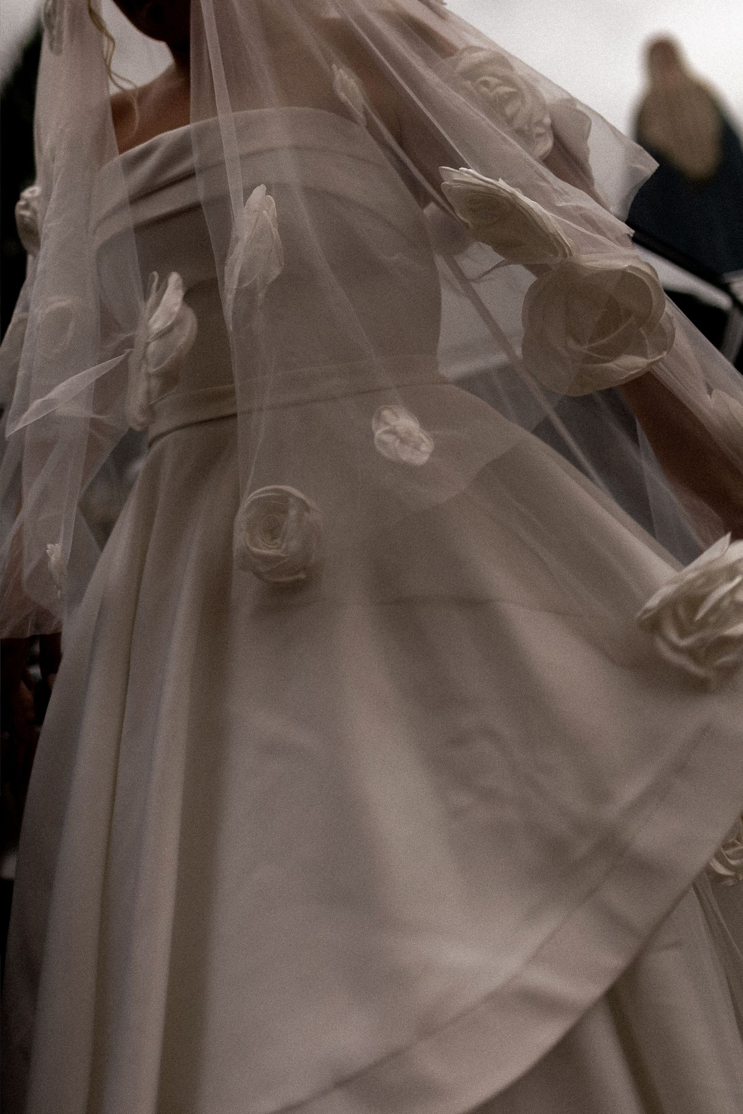 Elegant wedding dress with floral rose appliques on tulle veil detail close-up.