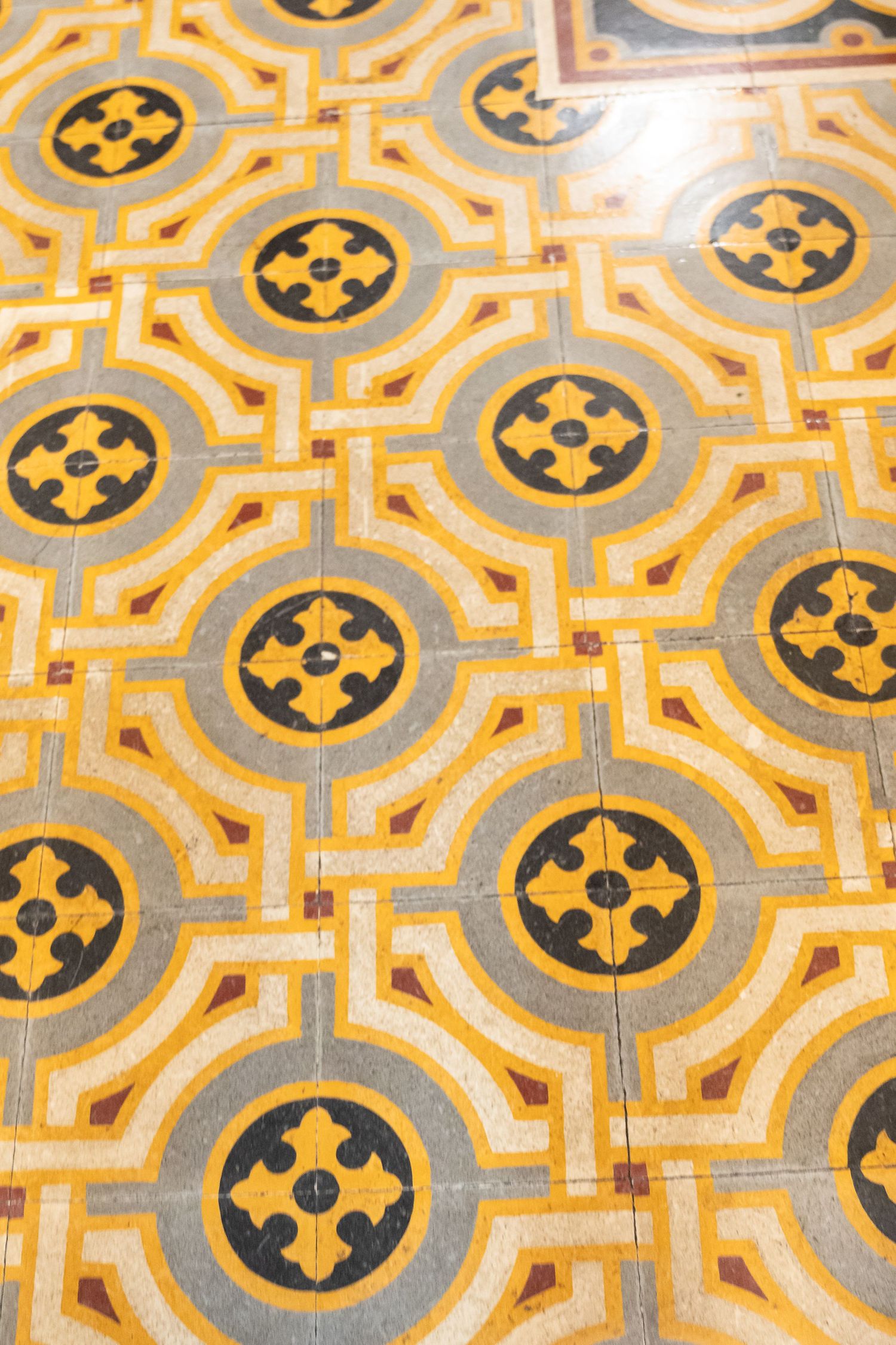 Vintage decorative floor tiles with yellow and black geometric floral pattern in circular medallion design.