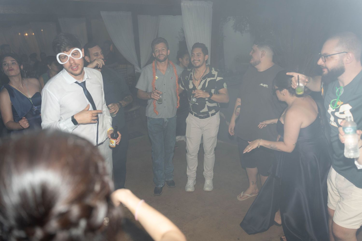 Group of people dancing and socializing at an indoor party event in a dimly lit venue.