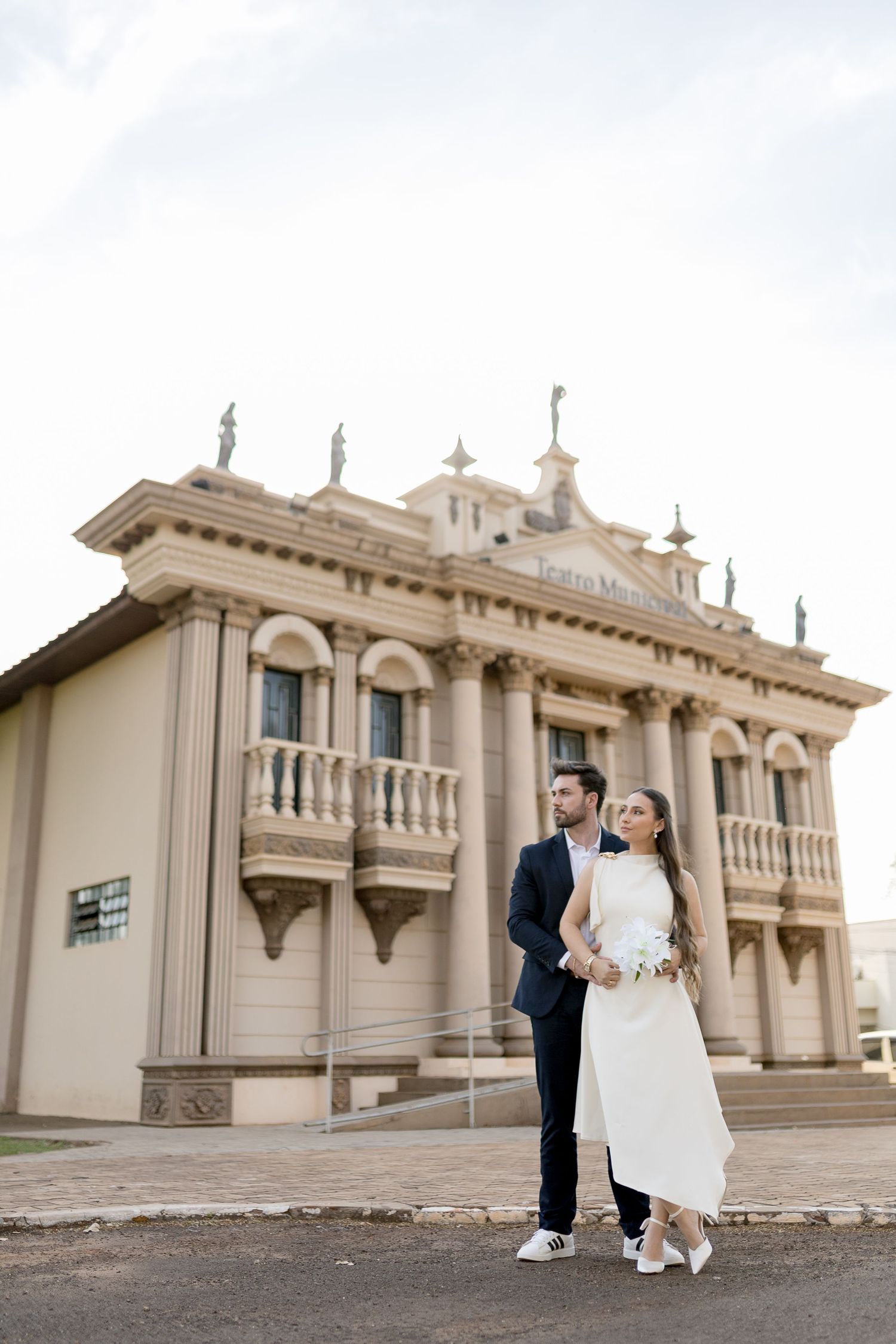 Bride and groom pose in front of a grand neoclassical building on their wedding day.