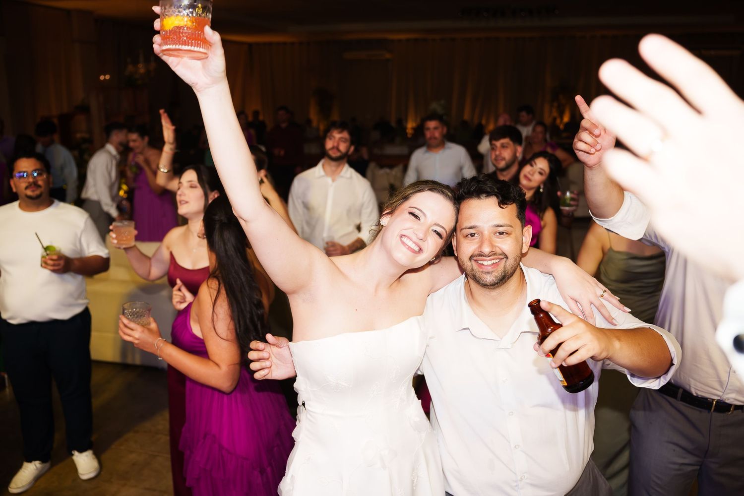 Bride and groom celebrate joyfully on the dance floor with guests at their wedding reception.
