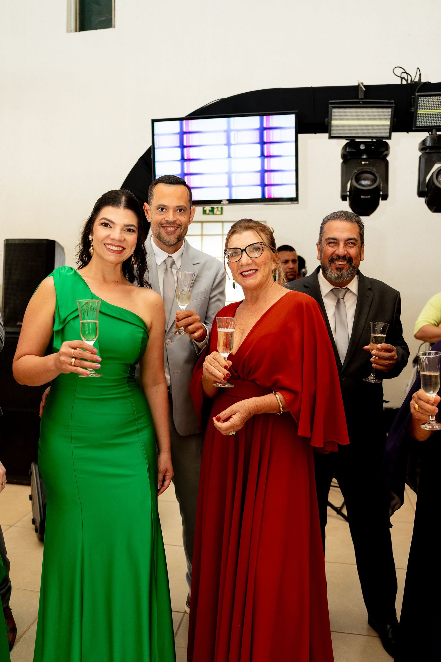 Elegantly dressed guests toasting with champagne glasses at a formal event, wearing green and red gowns.