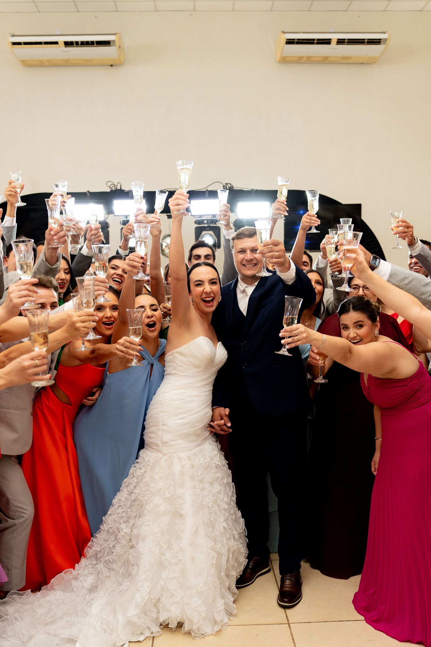 Bride and groom celebrate with wedding guests raising champagne glasses in a joyful toast at their reception.