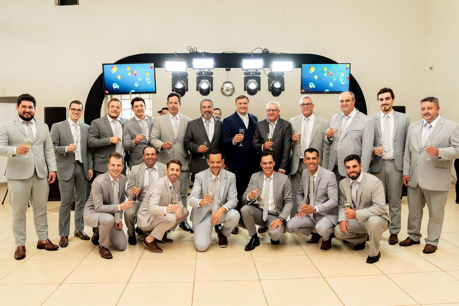 Large group of men in matching gray suits posing together for a formal group photo indoors.