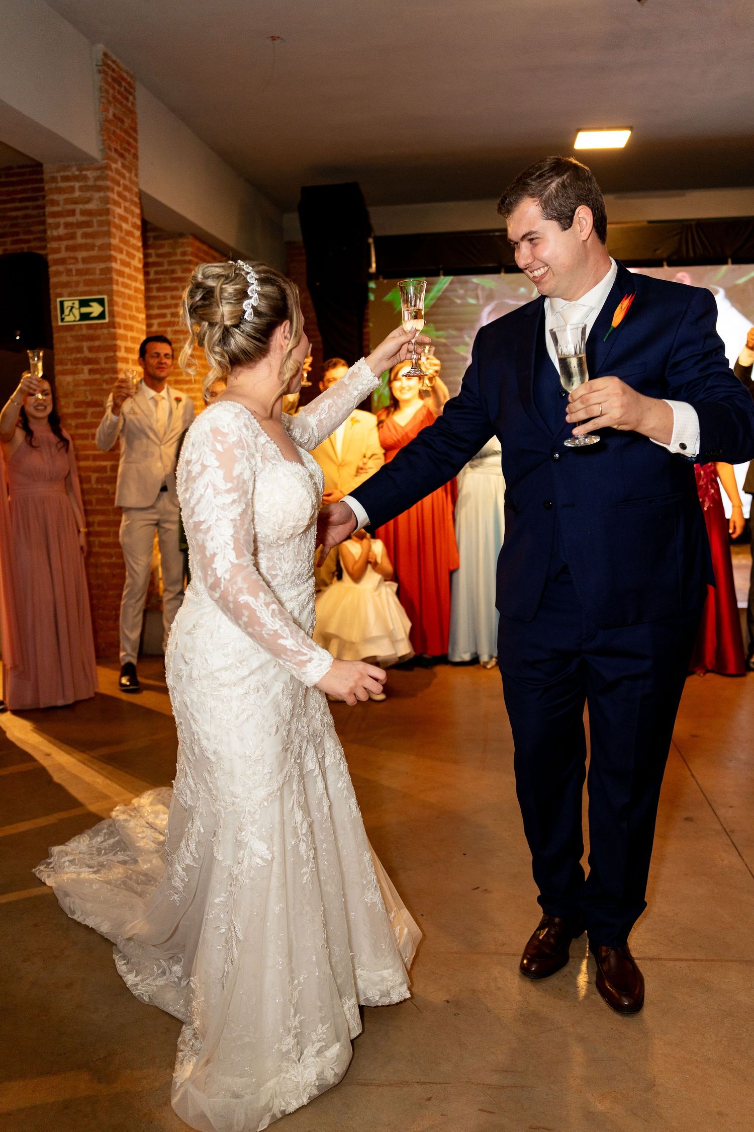 Bride and groom toast with champagne glasses while dancing at elegant wedding reception celebration.