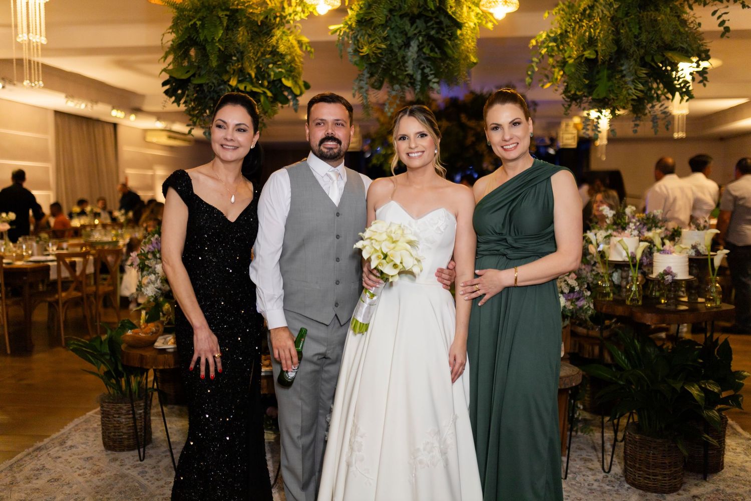 Bride and groom pose with two women in elegant attire at a beautifully decorated wedding reception venue.