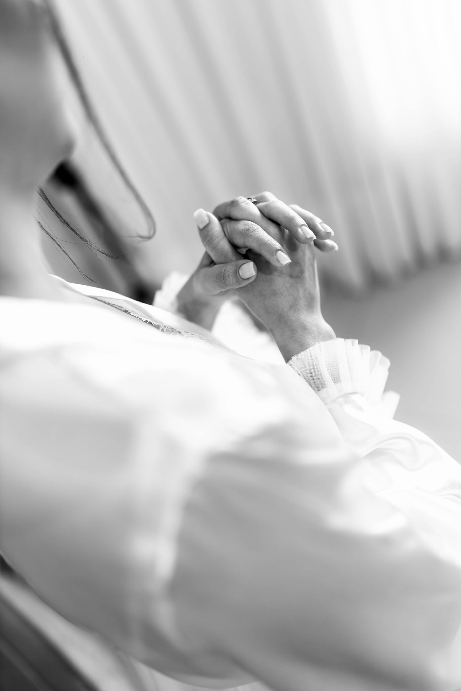 Black and white photo of two people holding hands tenderly, symbolizing comfort and care.