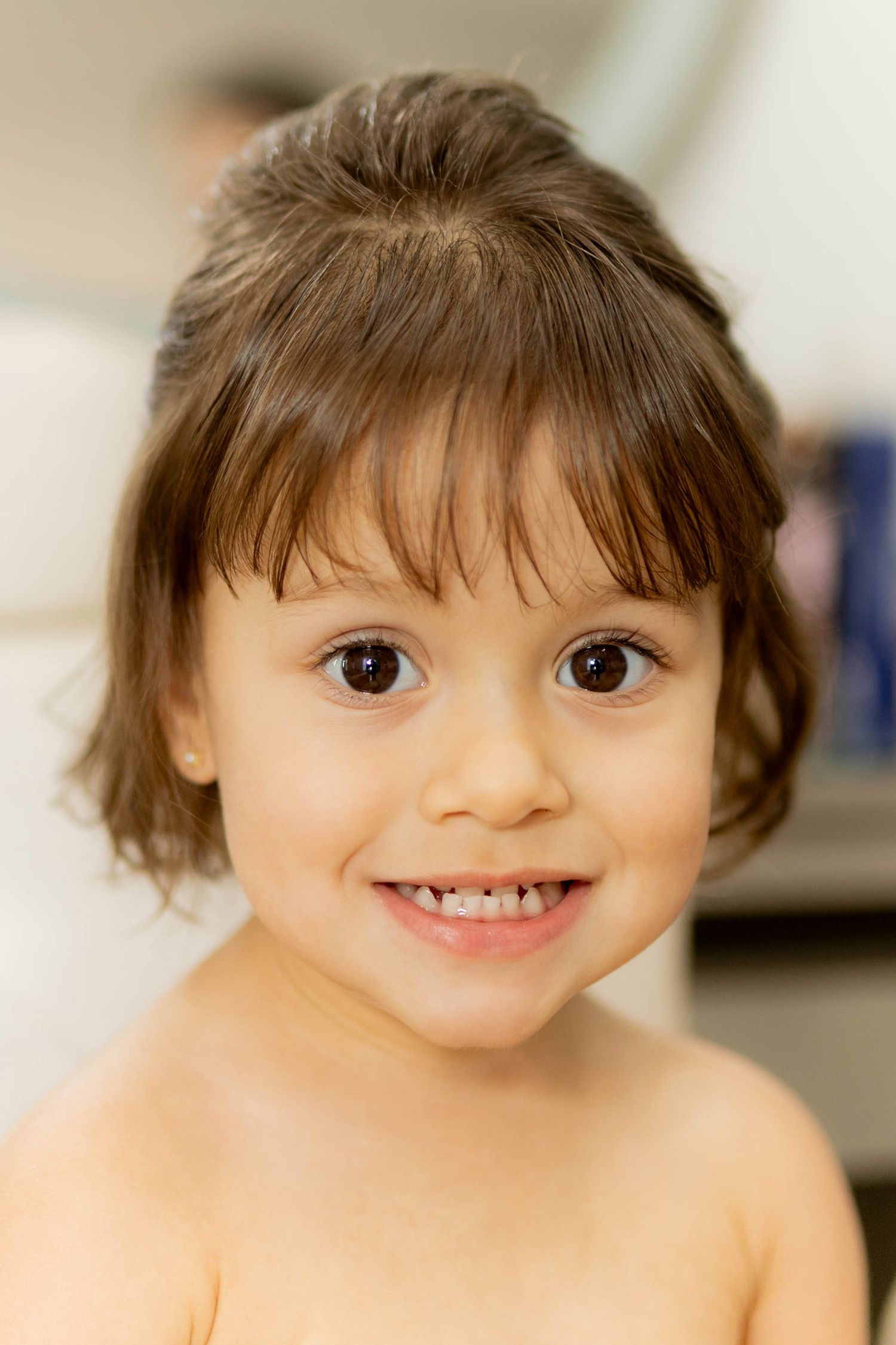 A smiling toddler with brown eyes and short dark hair poses for a cheerful portrait photo.
