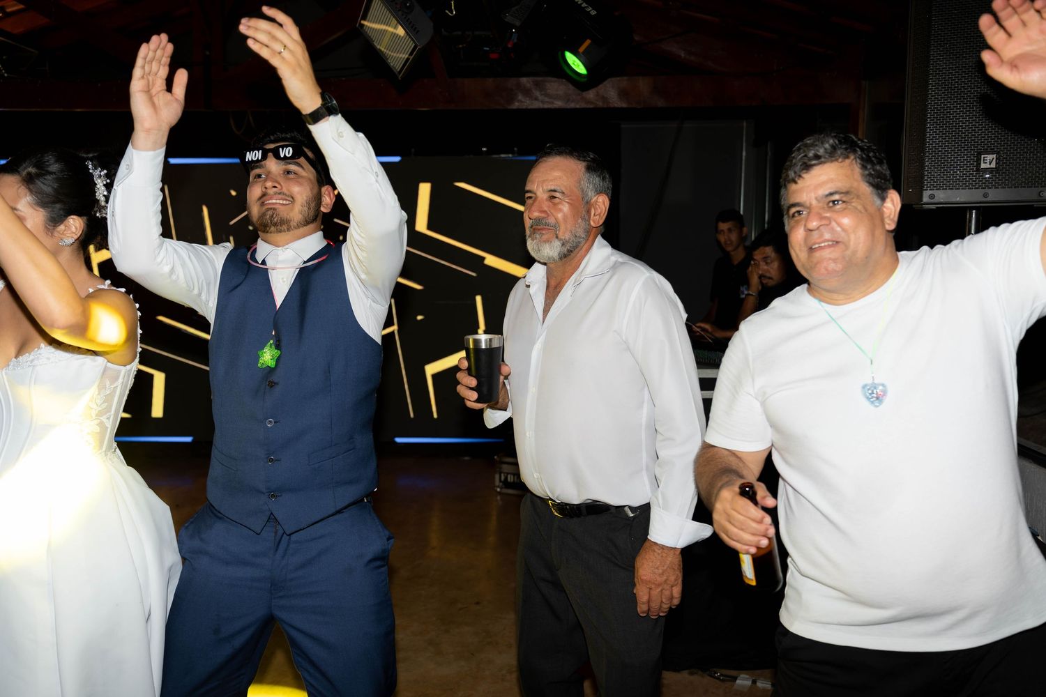 Men dancing and celebrating at an indoor party event with neon lights in the background.