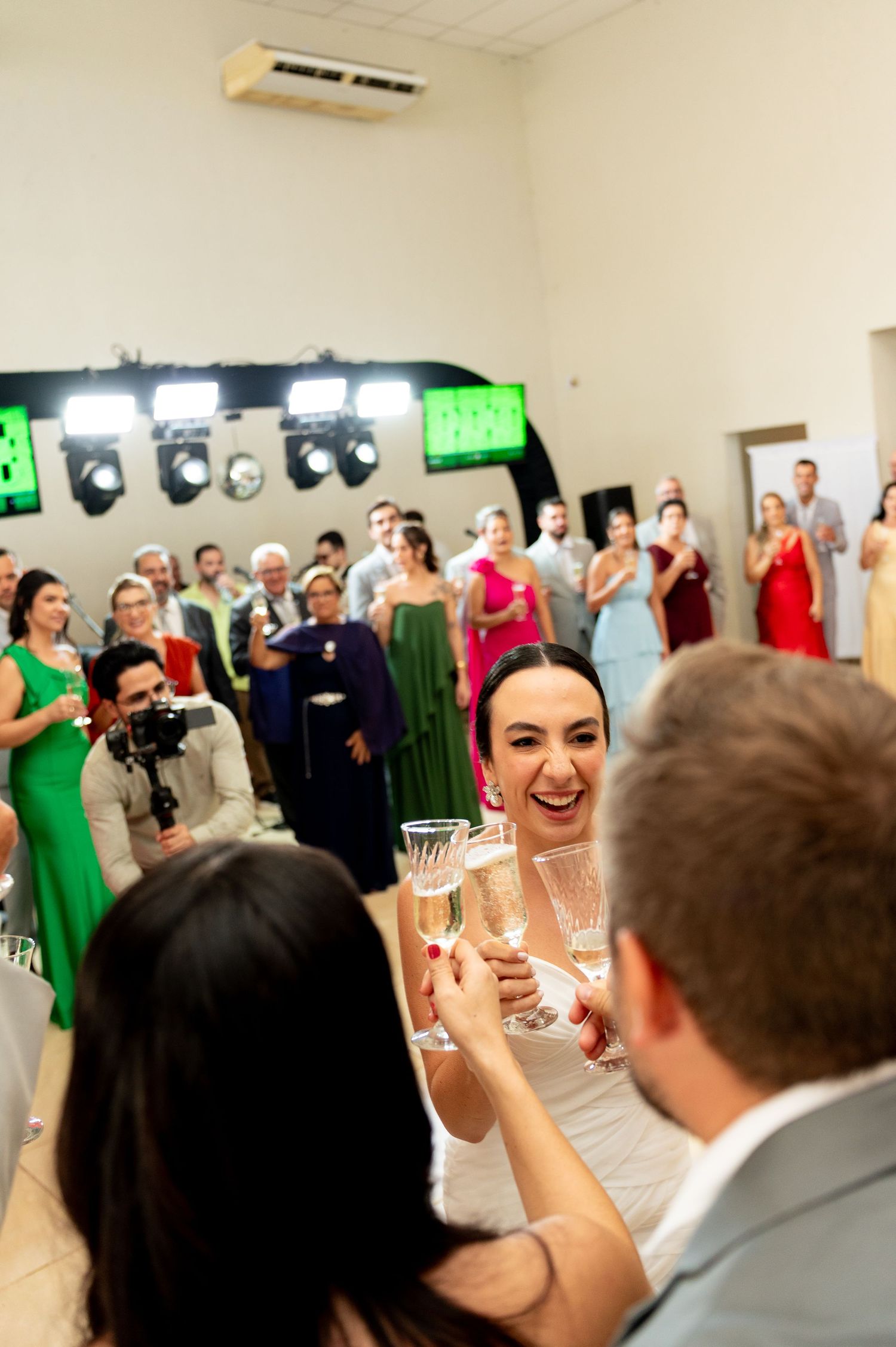 Bride laughing and toasting champagne glasses with guests at a wedding reception celebration.