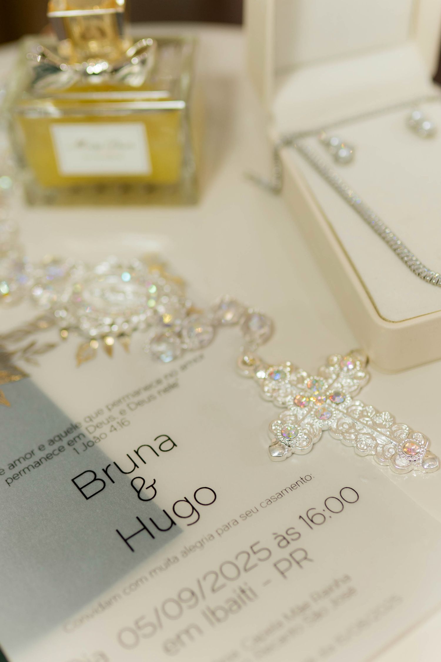 Elegant wedding invitation for Bruna and Hugo dated 05/09/2025, surrounded by crystal jewelry and perfume bottle.
